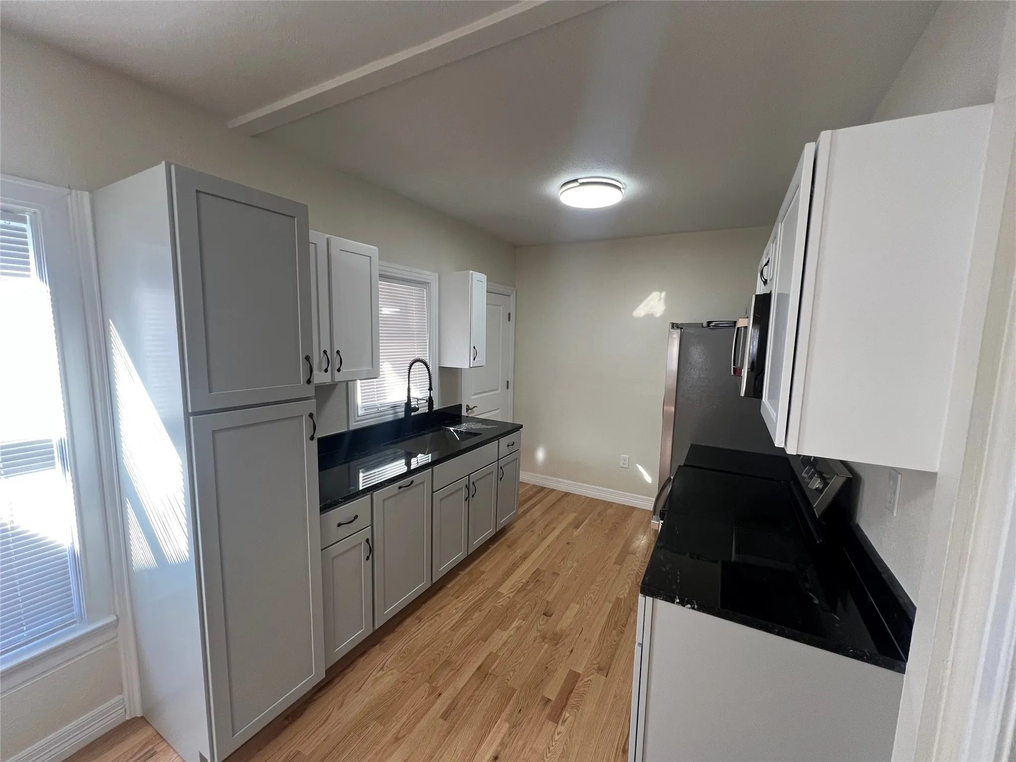 Kitchen featuring light wood-type flooring, plenty of natural light, gray cabinetry, and sink