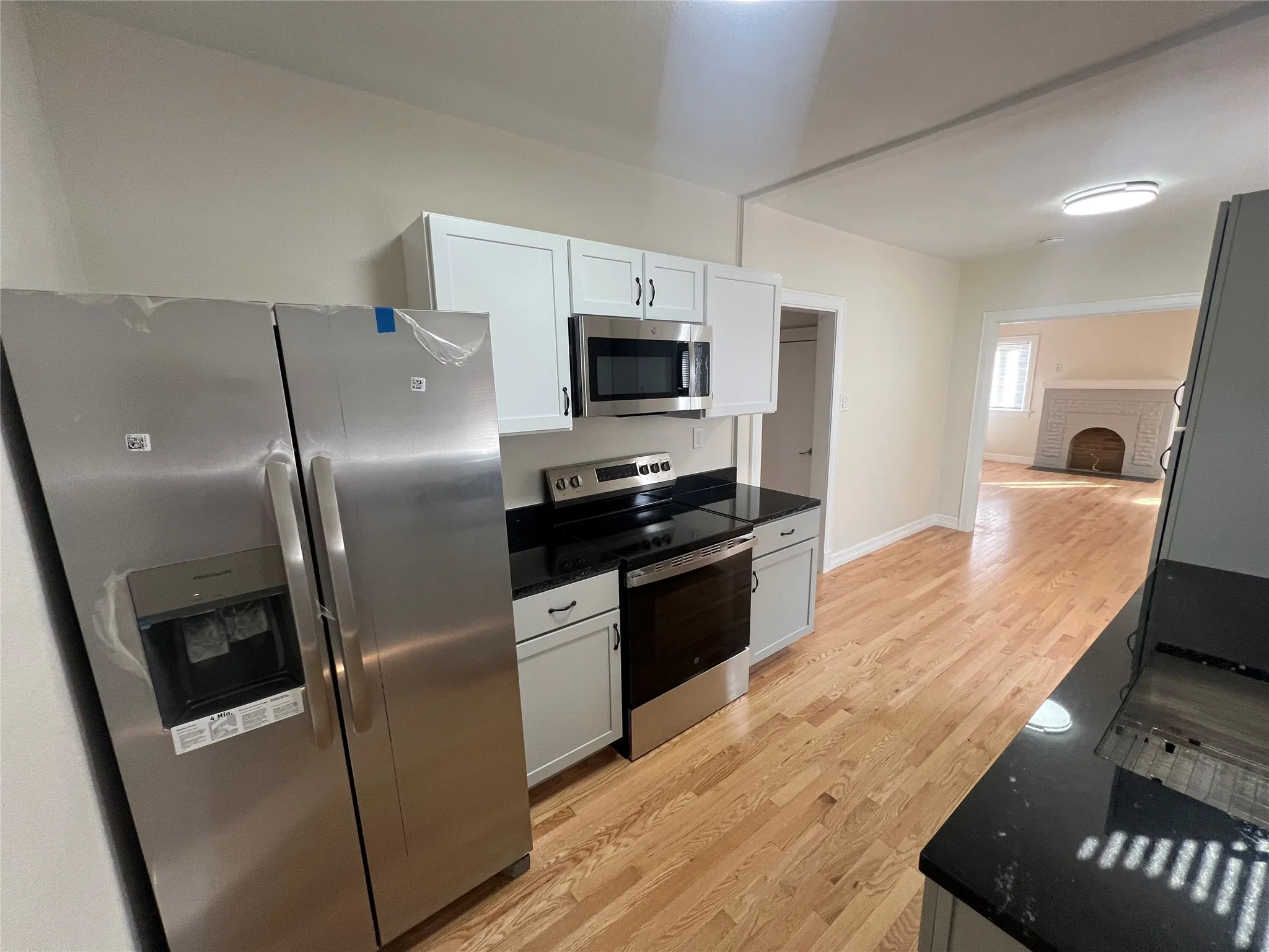 Kitchen with light wood-type flooring, white cabinetry, and stainless steel appliances