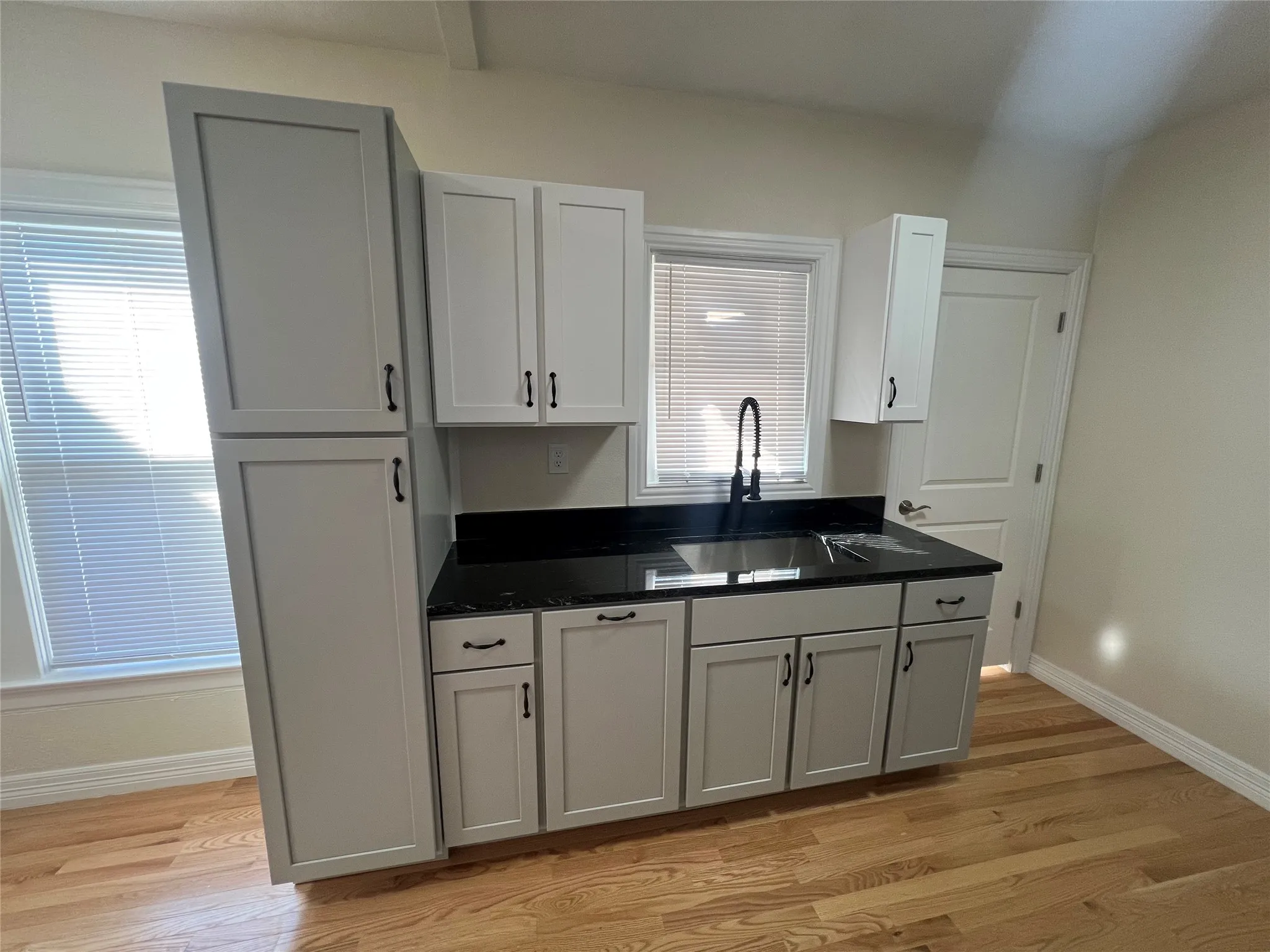 Kitchen with gray cabinets, light hardwood / wood-style flooring, and sink