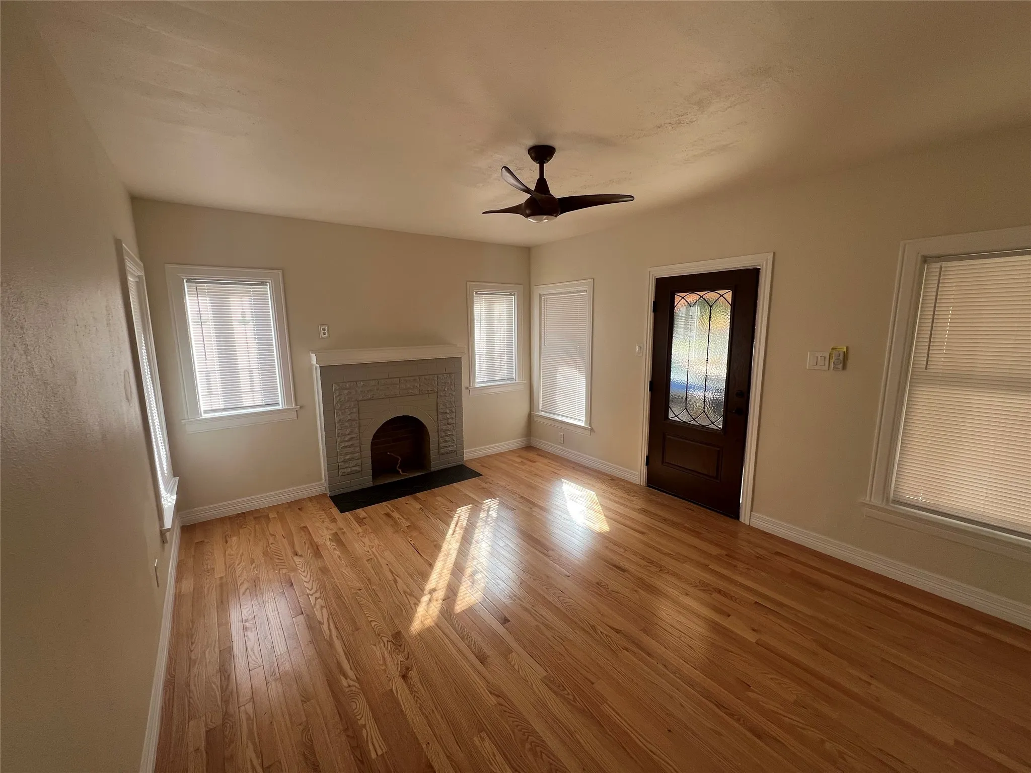 Unfurnished living room with ceiling fan, a fireplace, and light hardwood / wood-style floors