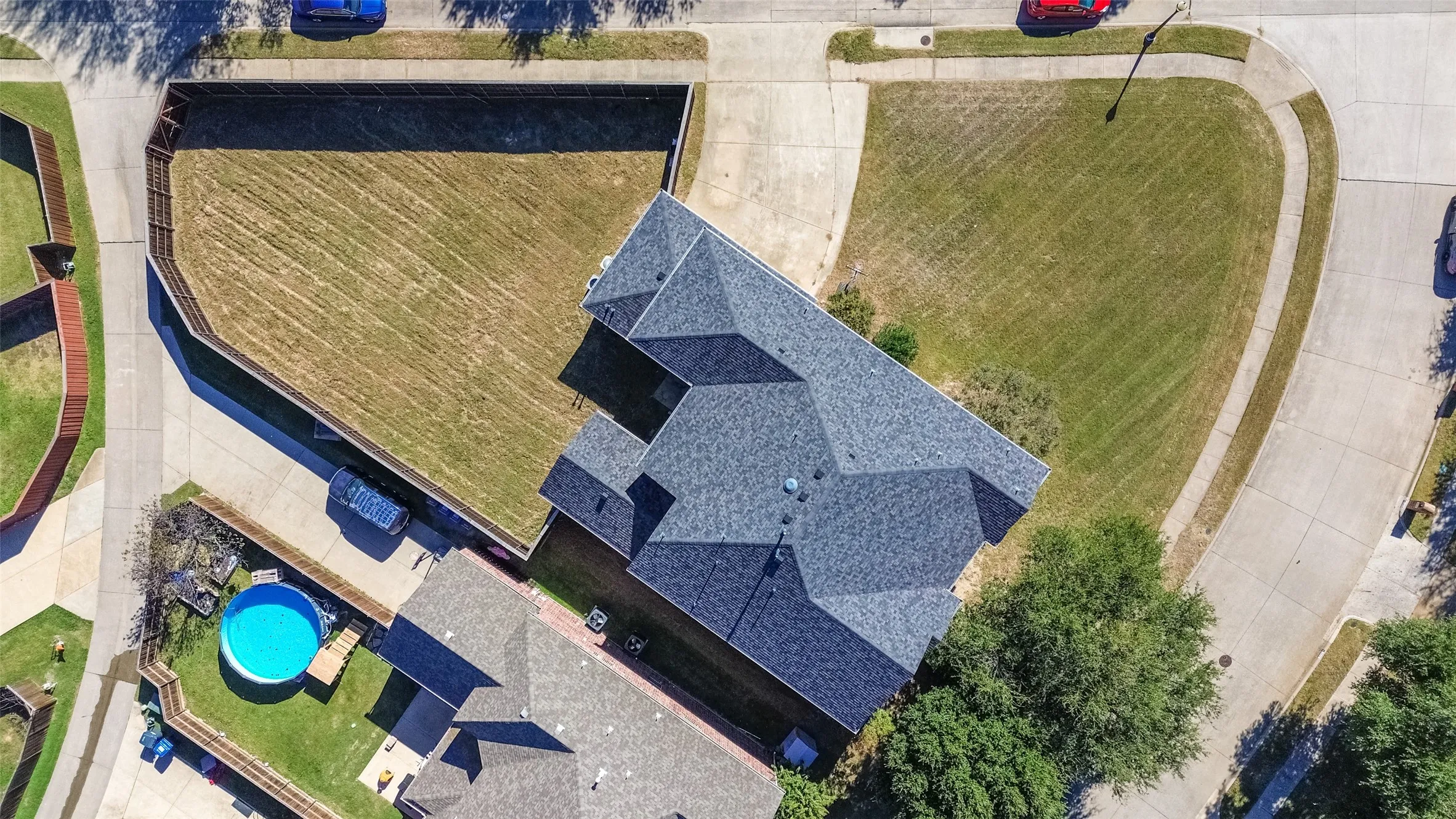 Aerial view showcasing a property with a multi-gabled roof and a spacious, fenced backyard
