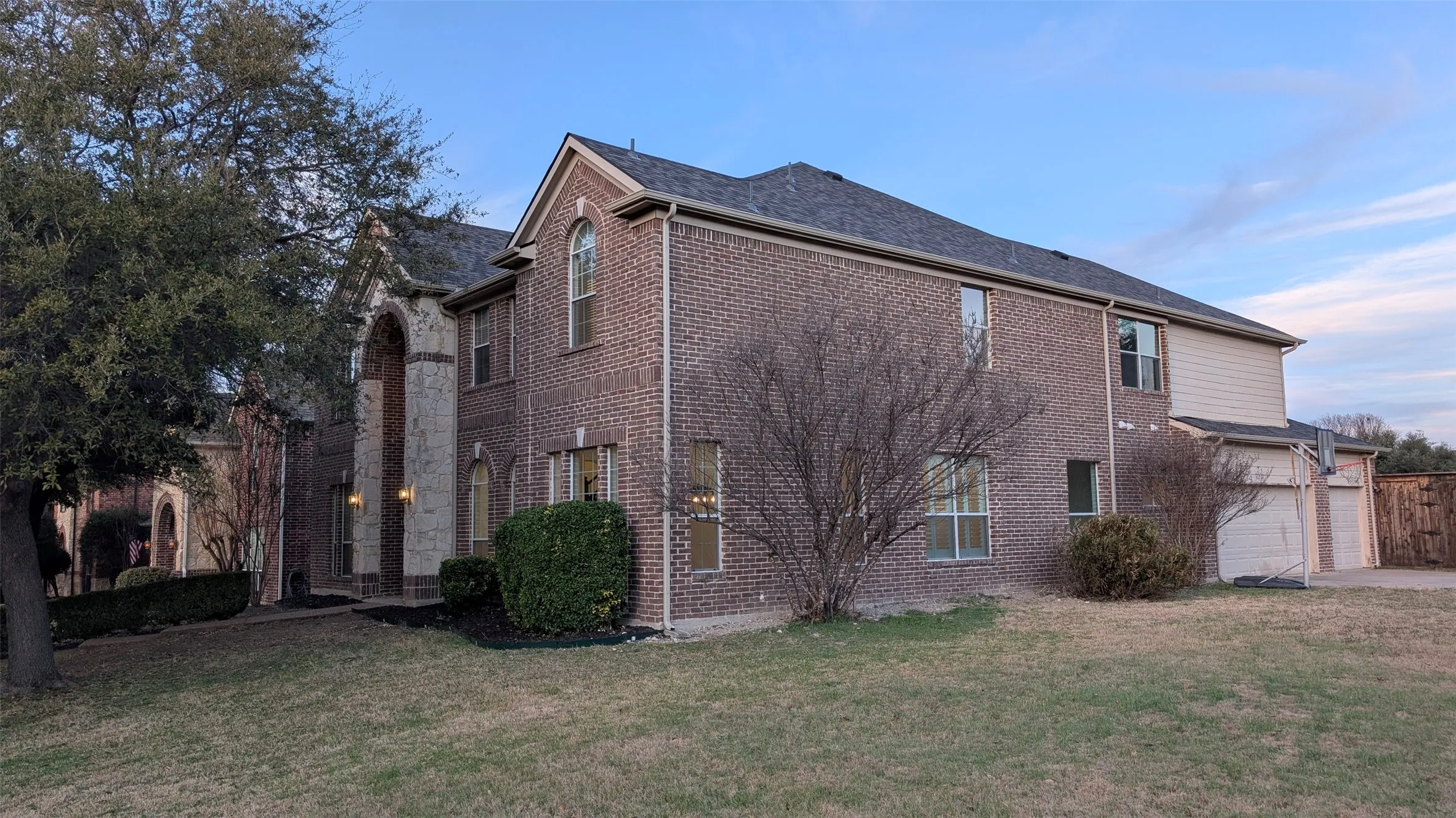 Brick two-story residence featuring a stone archway entry, arched and rectangular windows, and a multi-car garage
