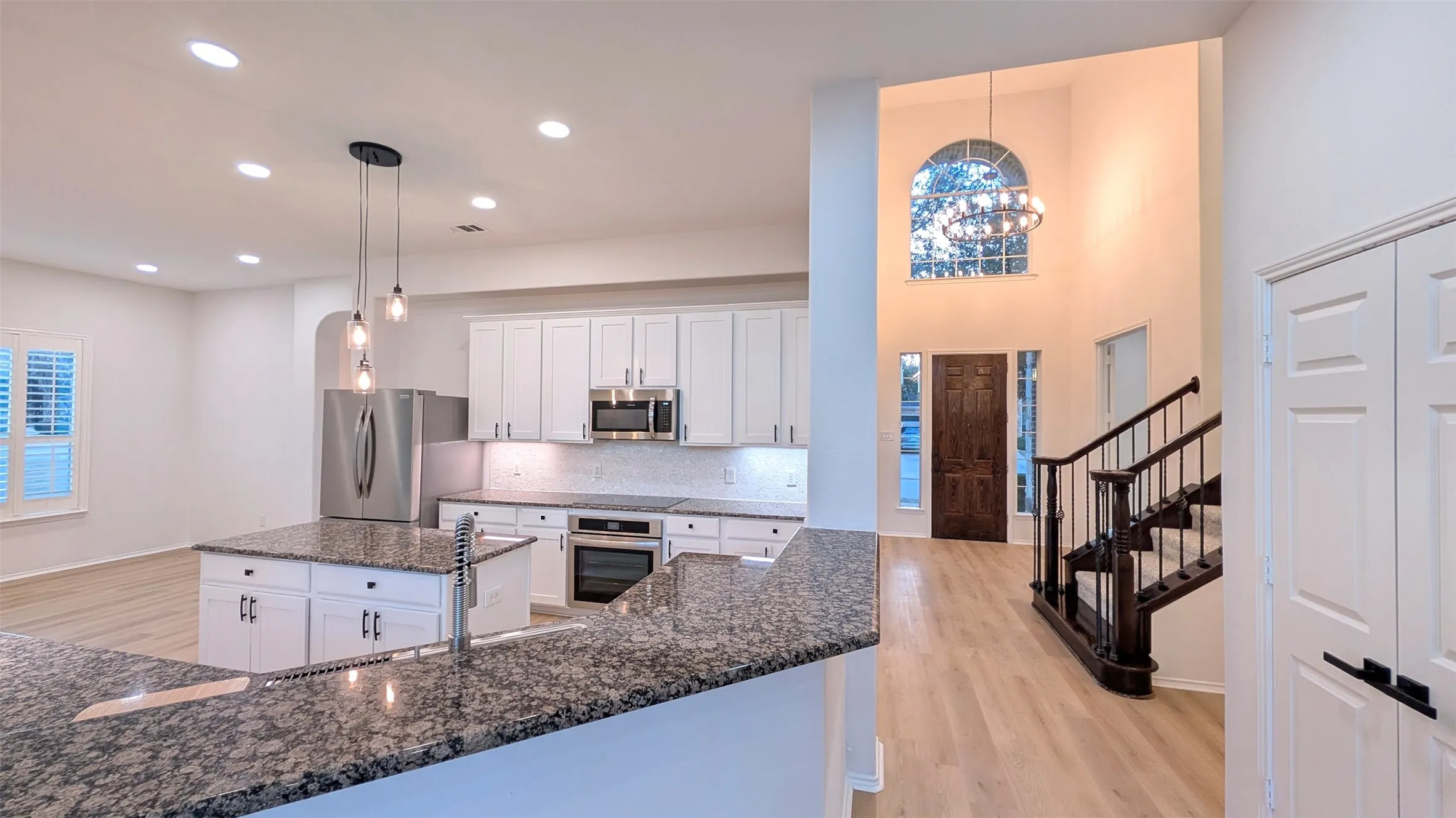 Open-concept kitchen featuring white cabinetry, stainless steel appliances, and granite countertops