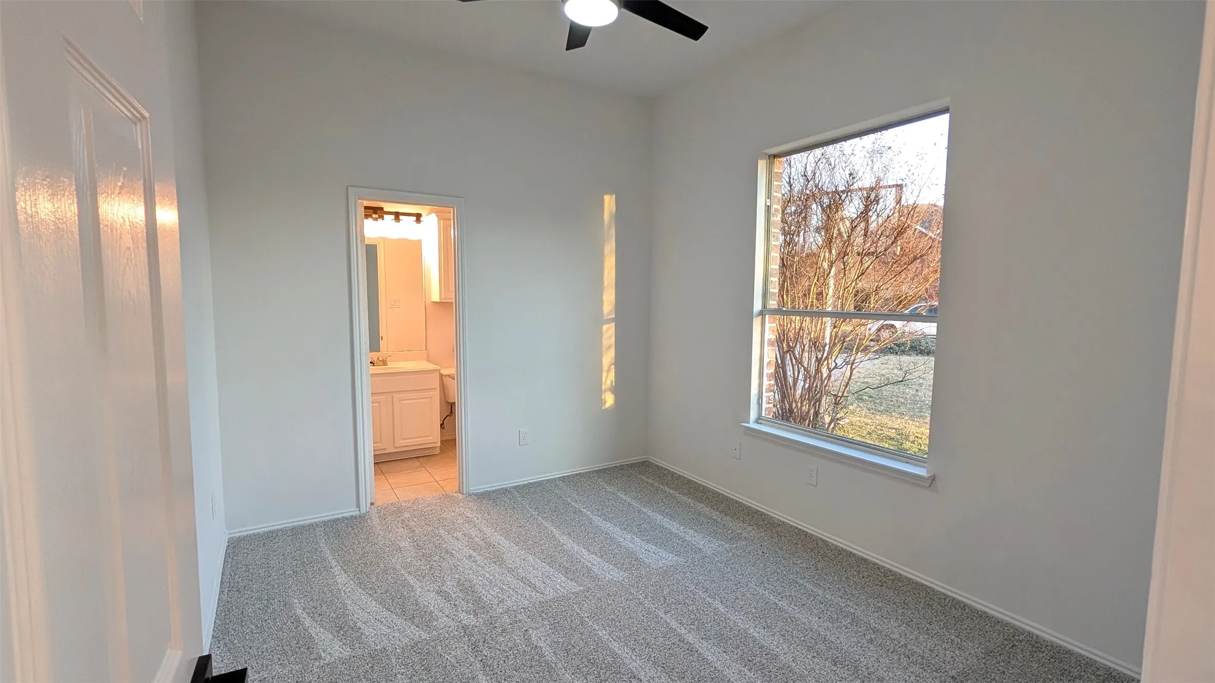 Spacious room featuring vaulted ceilings, a contemporary ceiling fan, and patterned carpeting