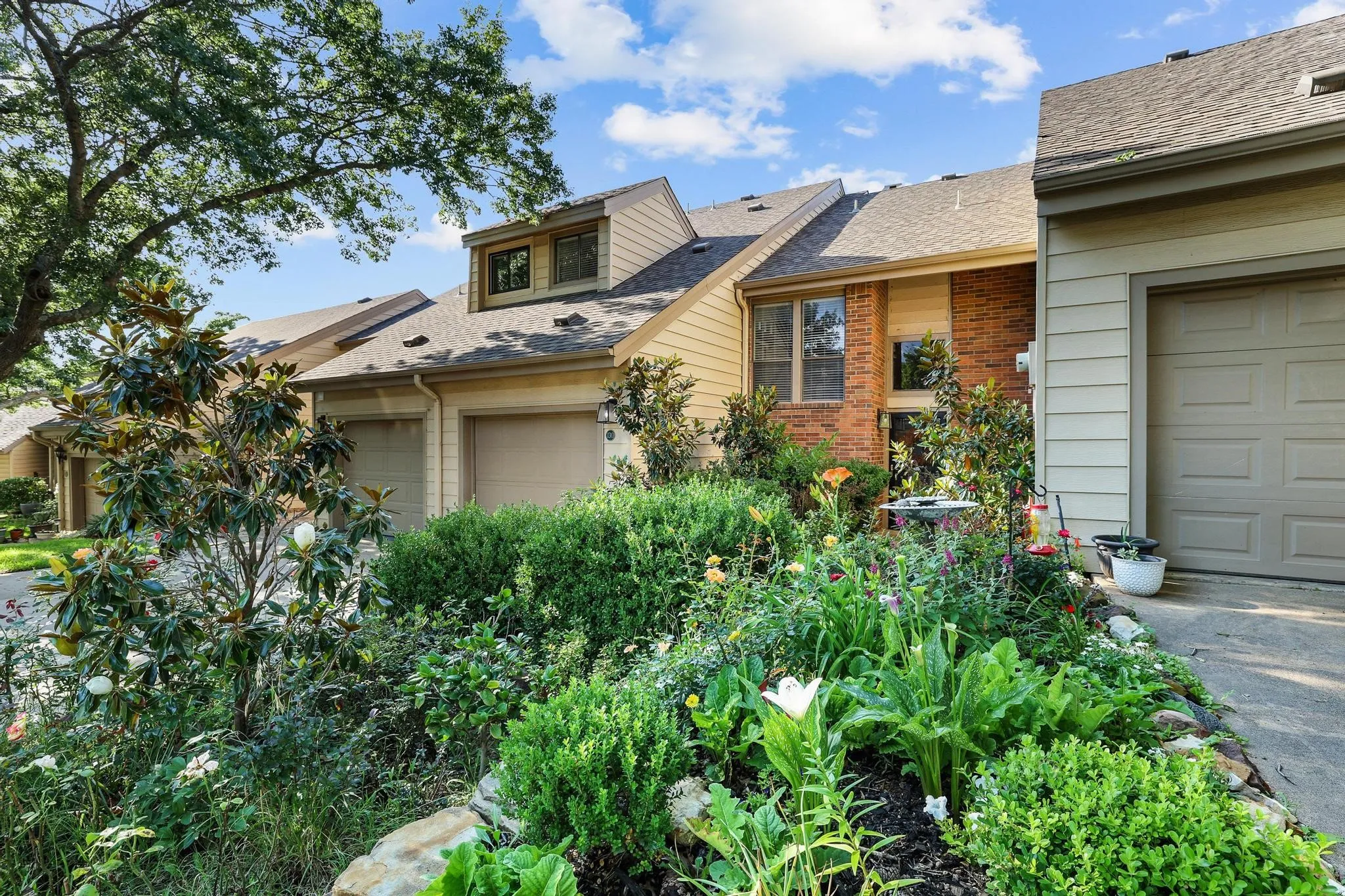 Entryway features lush landscaping including roses and magnolias