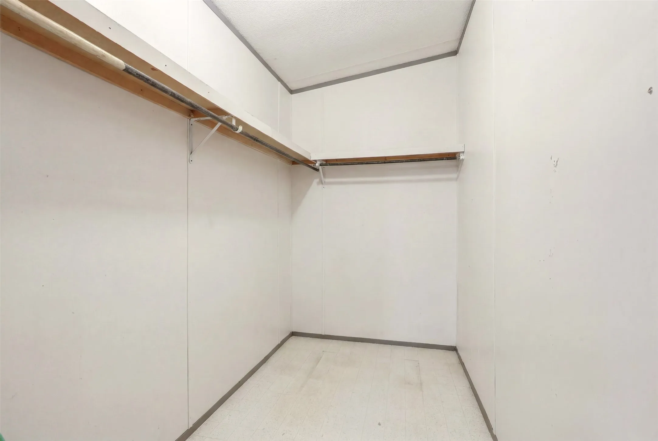 Walk-in closet featuring white wall panels and light-toned flooring