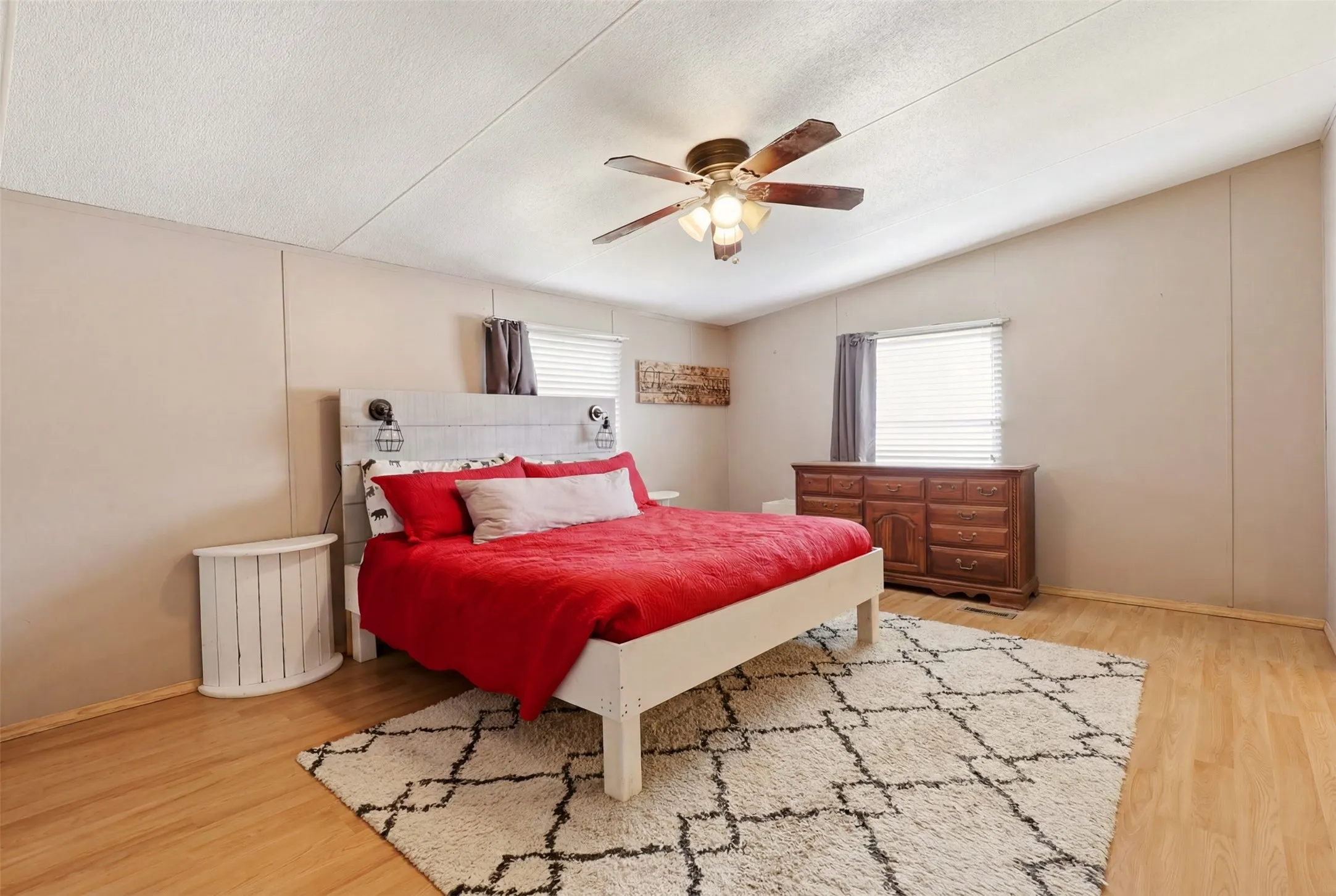 Spacious room featuring light wood-finish flooring and a ceiling fan with integrated lighting