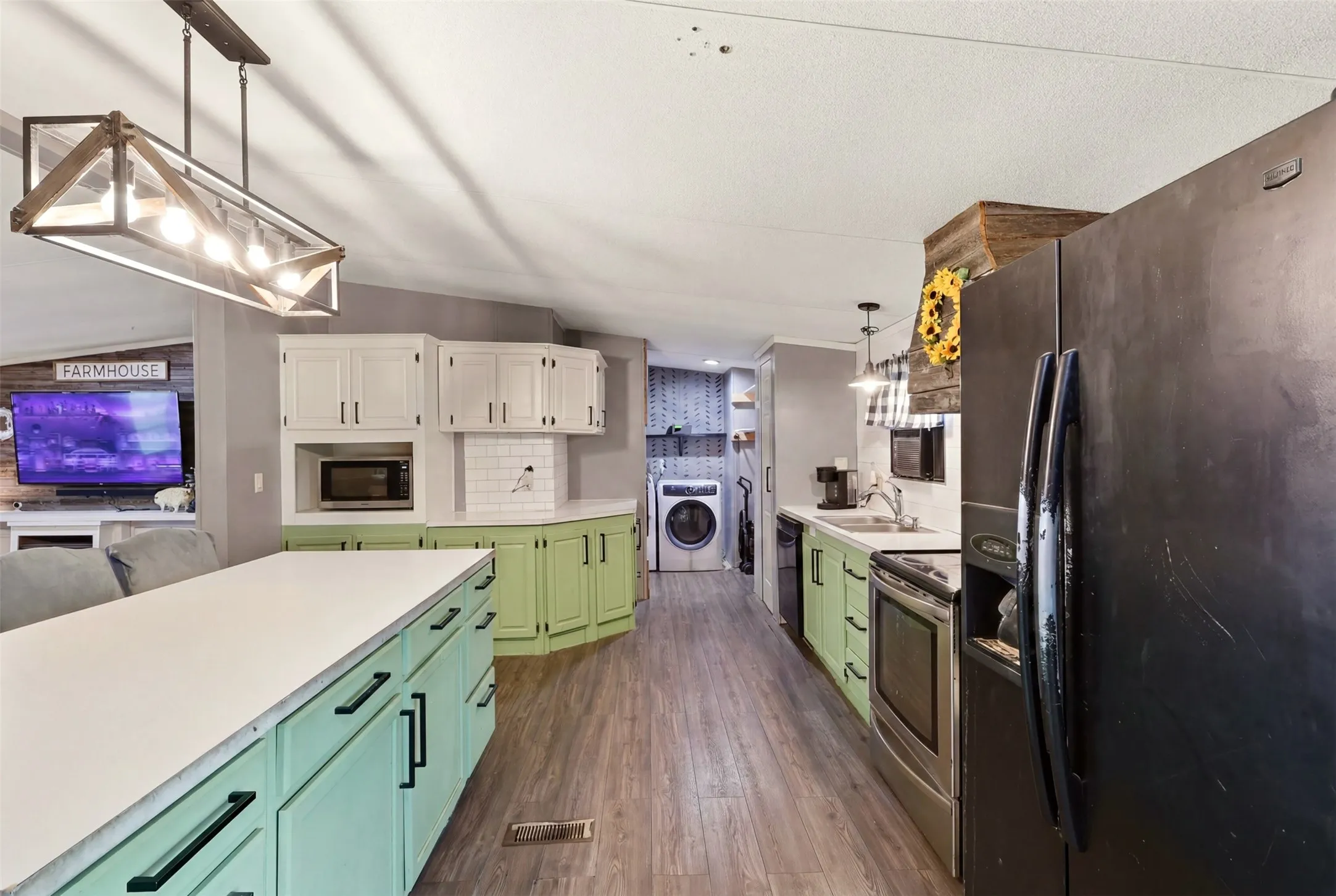 Contemporary kitchen featuring wood-finish flooring and a central island with a light-colored countertop