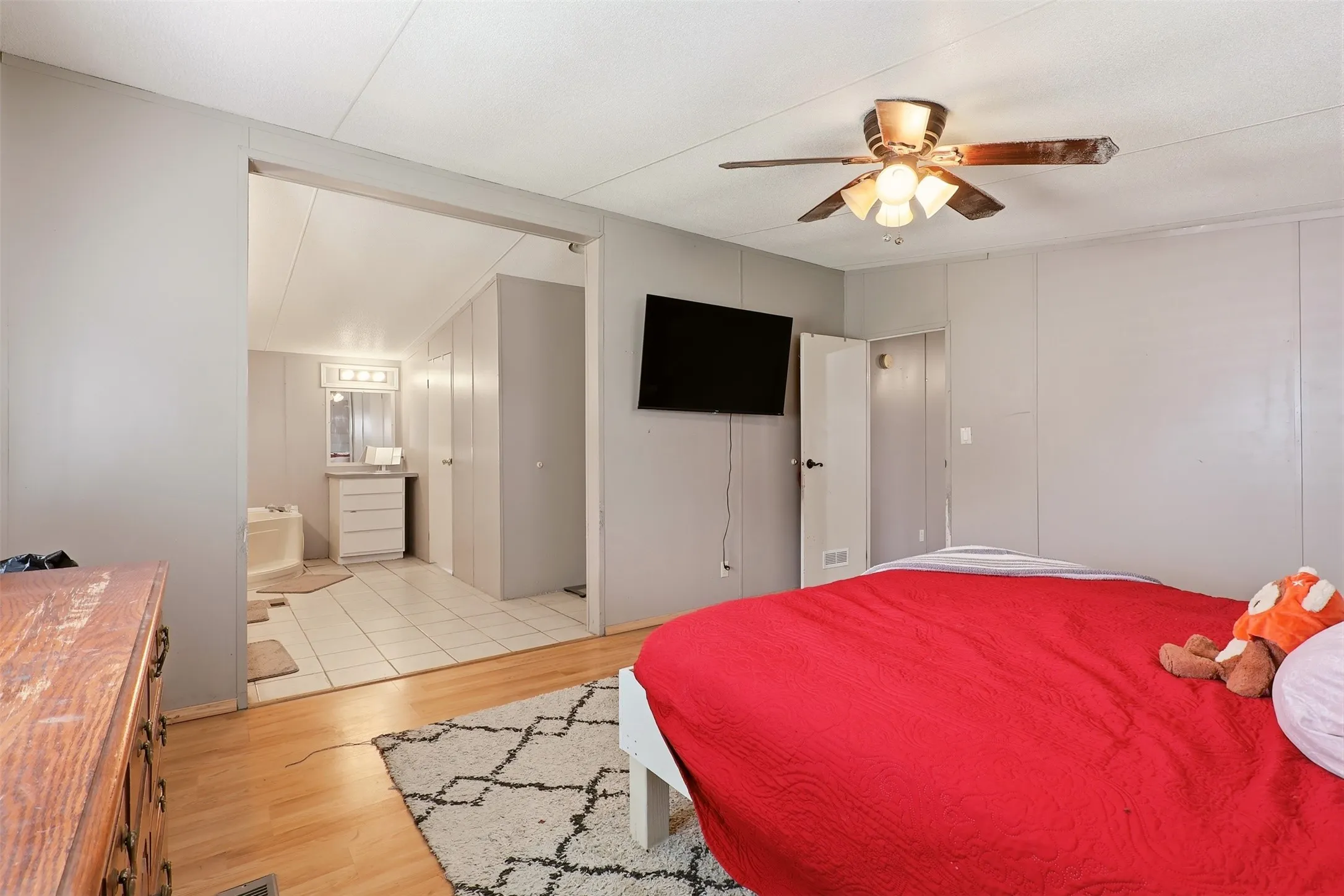 Bedroom featuring wood-finish flooring, a ceiling fan with integrated lighting, and direct access to an en-suite bathroom with tile flooring and a vanity