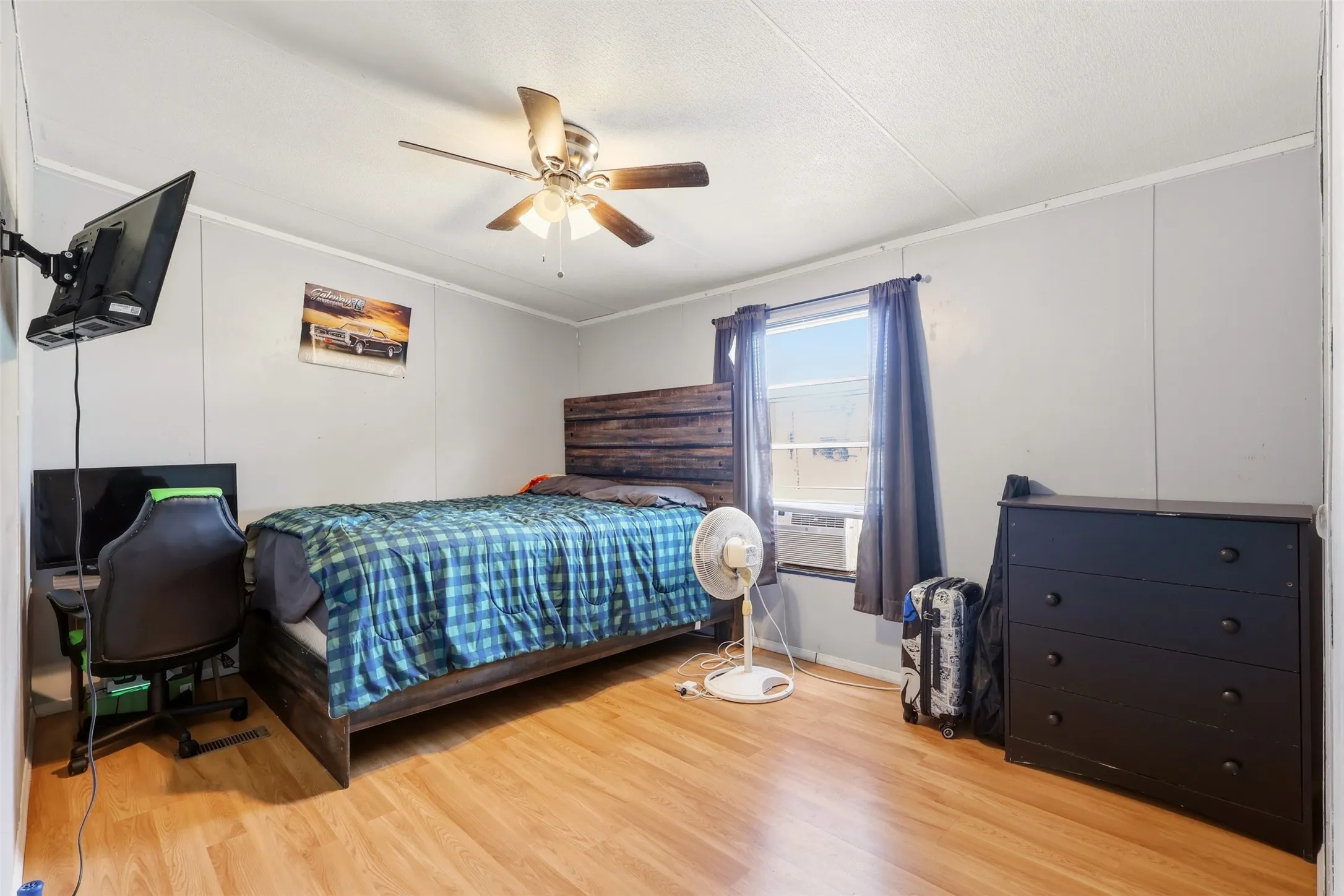 Room featuring wood-finish flooring, a ceiling fan with light fixture, and a window with blinds