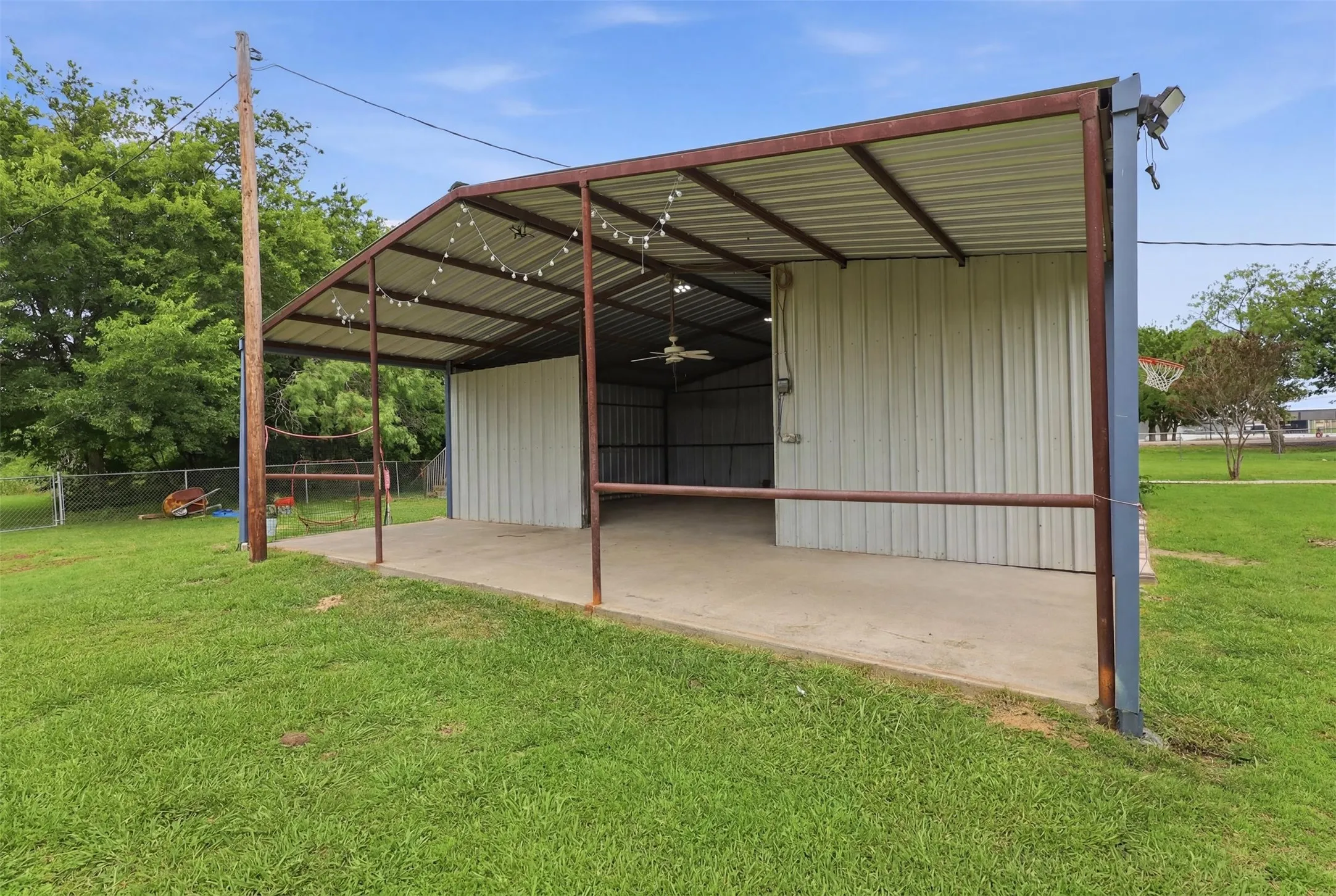 Metal-frame structure featuring a concrete slab foundation, corrugated metal roofing, and corrugated metal wall paneling