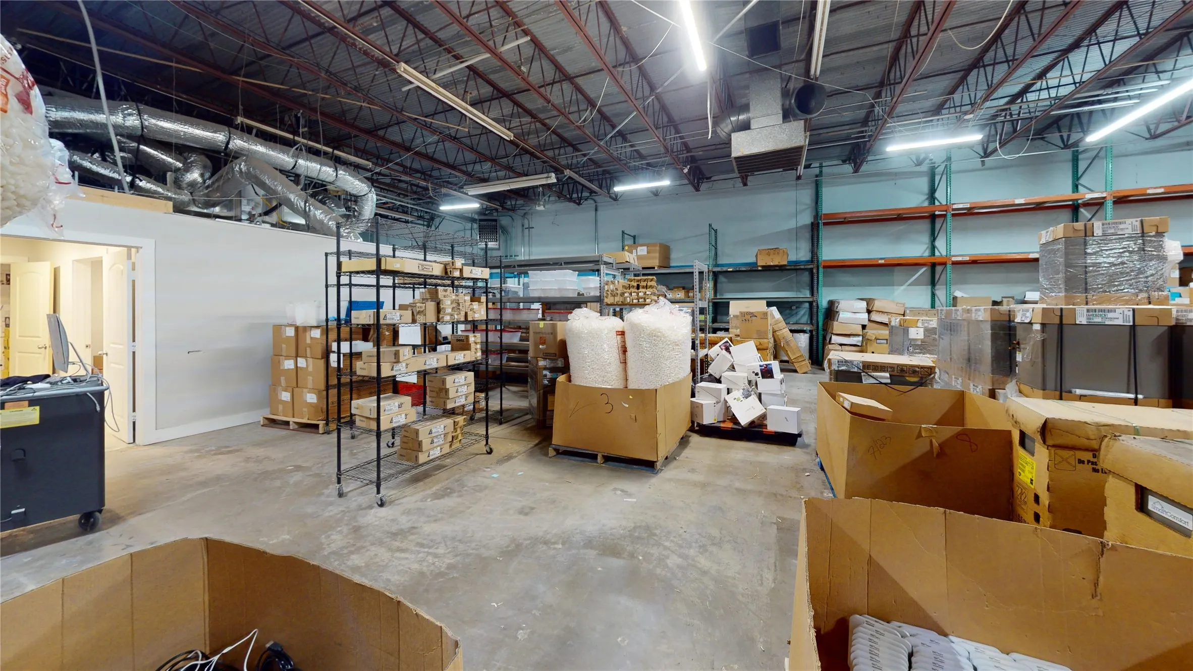 Spacious industrial warehouse interior with concrete flooring and exposed metal truss ceiling