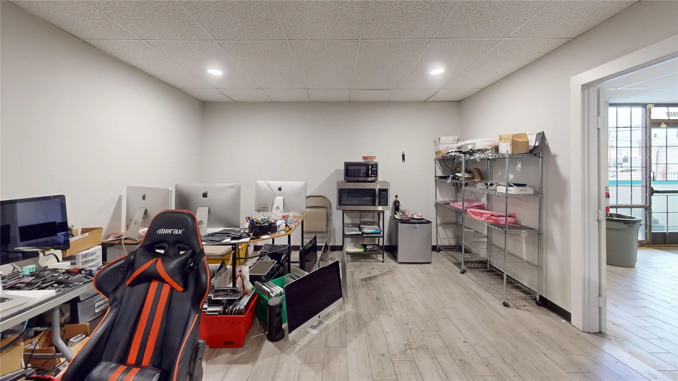 Spacious room featuring light wood-finish flooring, recessed lighting, white walls, and a dropped ceiling