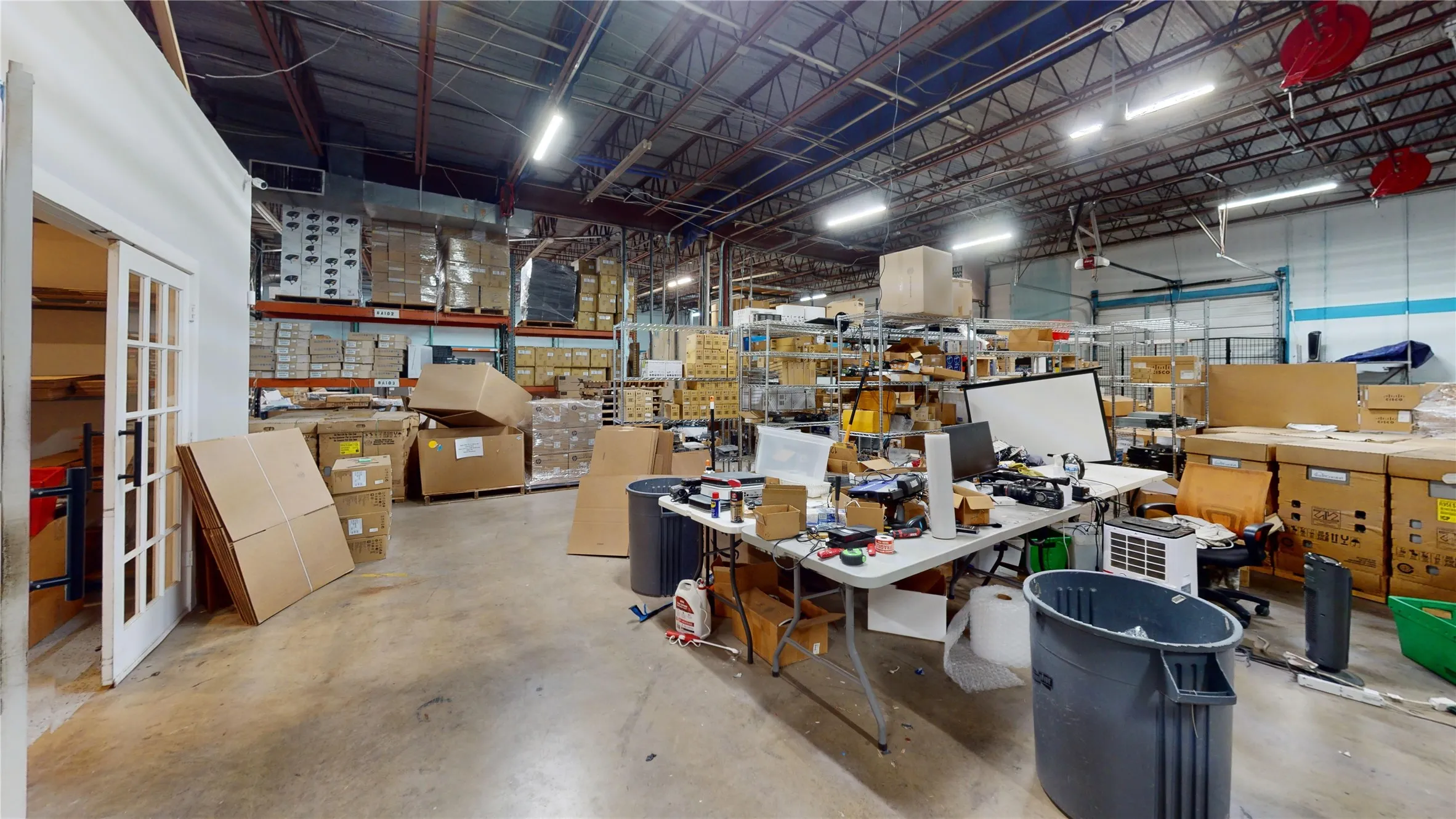 Industrial warehouse interior featuring exposed ceiling trusses, concrete flooring, and high-bay lighting