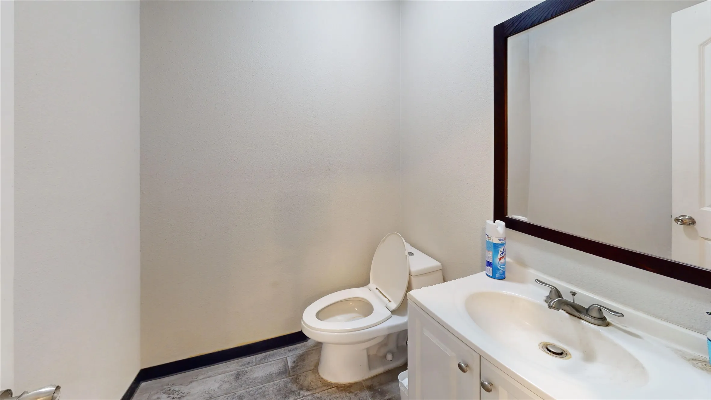 White vanity with integrated sink, chrome faucet, and dark framed wall mirror
