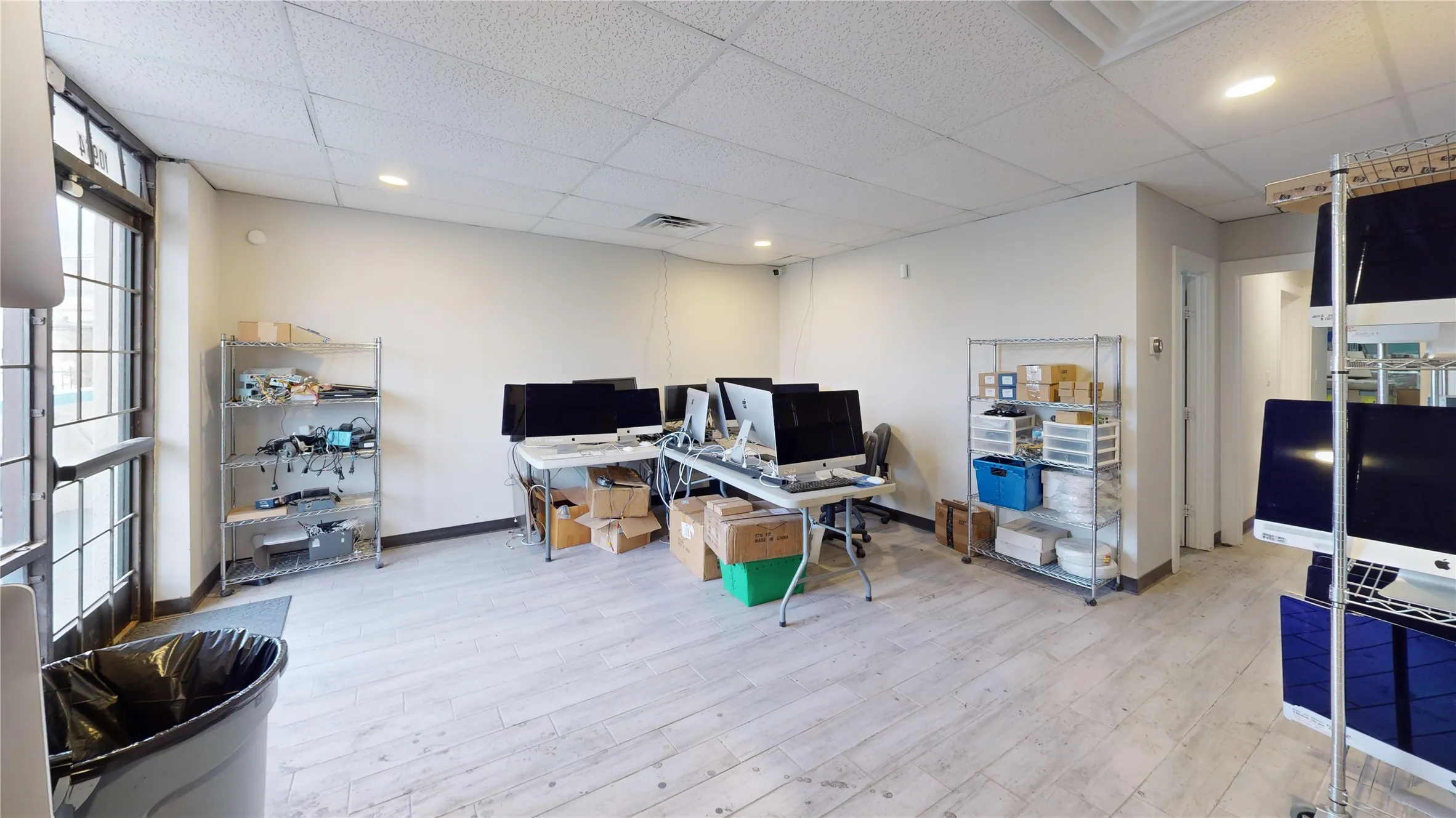 Spacious commercial interior featuring light wood-finish flooring, recessed lighting, and ample wall space