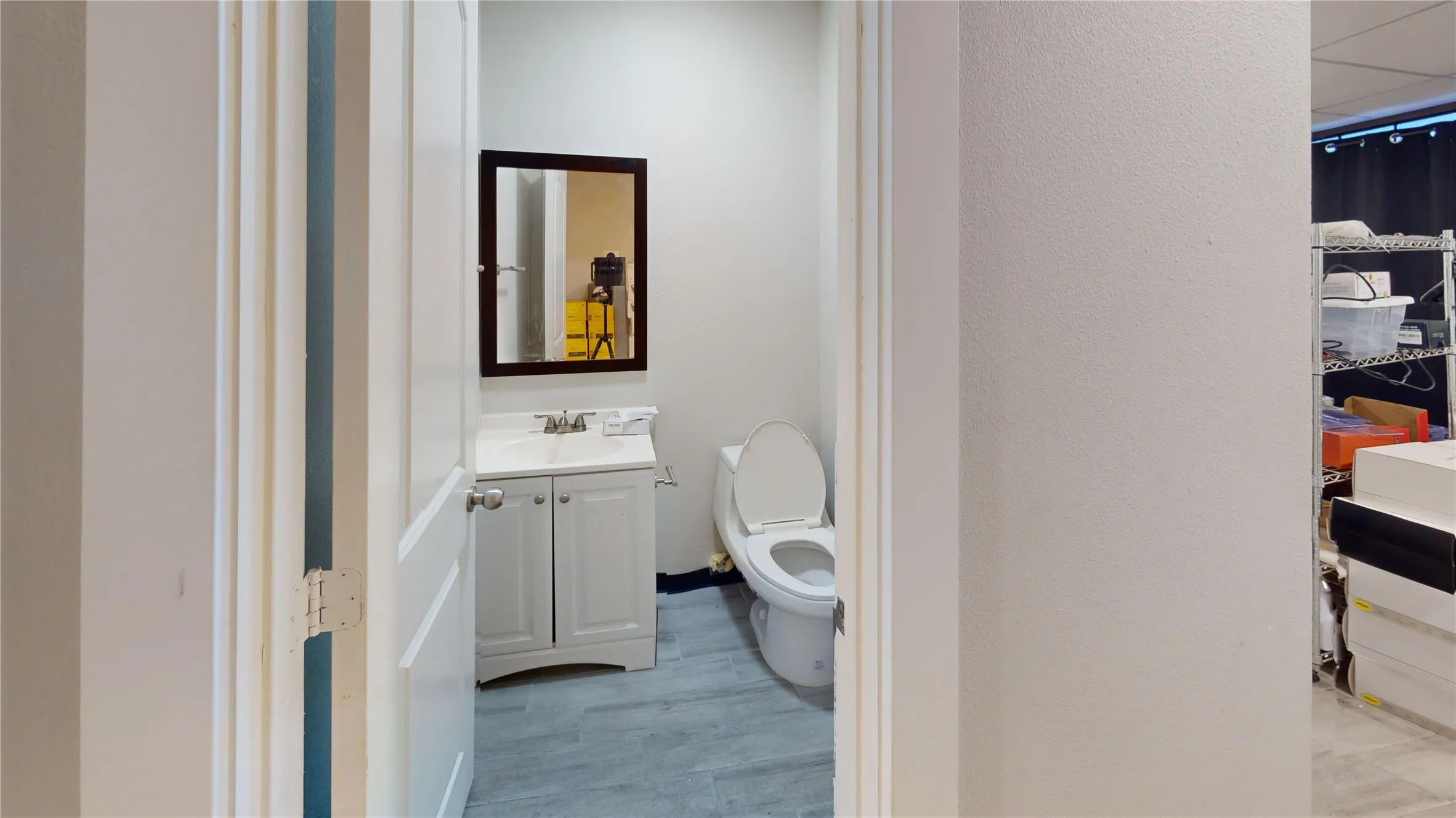 Bathroom featuring a vanity with a white cabinet, integrated sink, and an unframed mirror