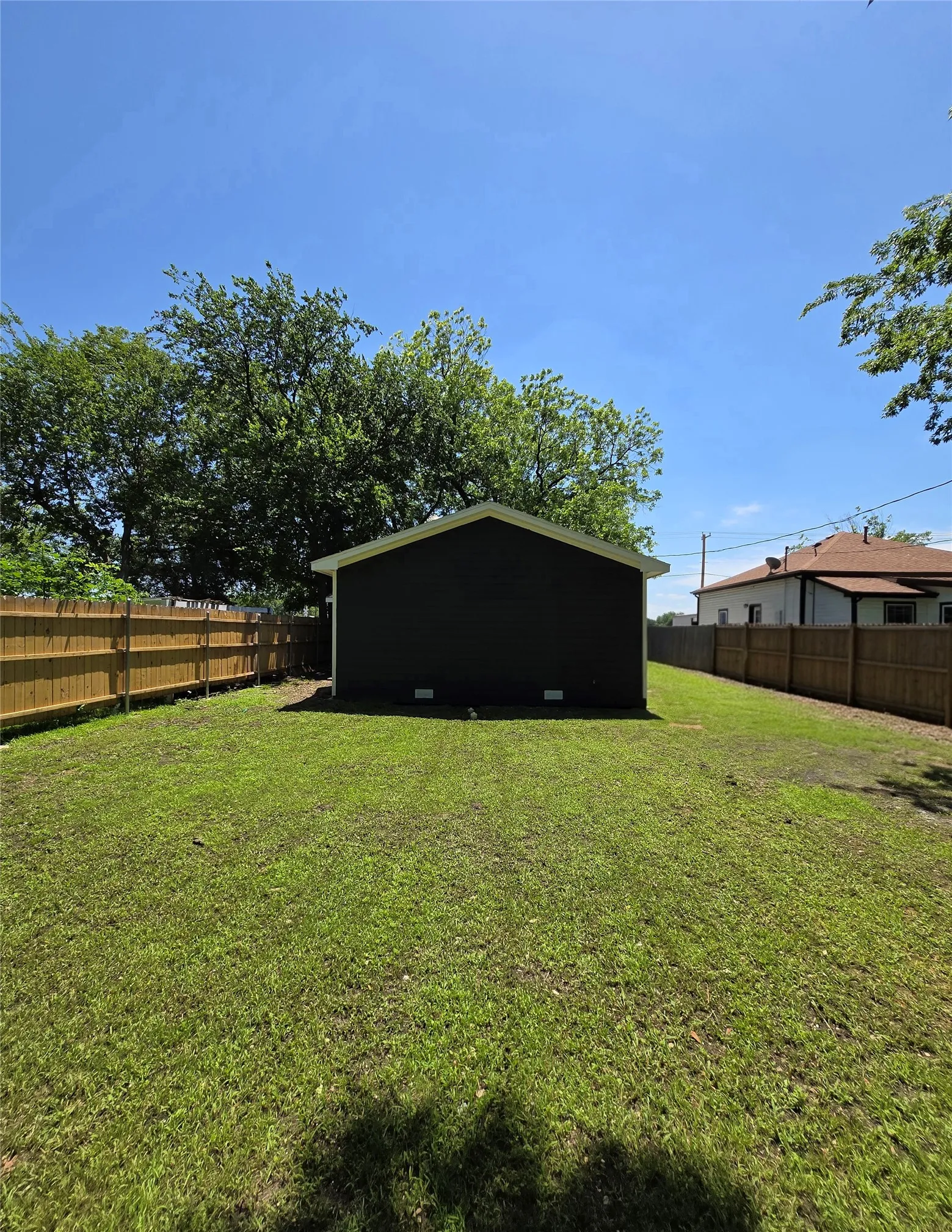 Expansive green lawn framed by a new wood privacy fence