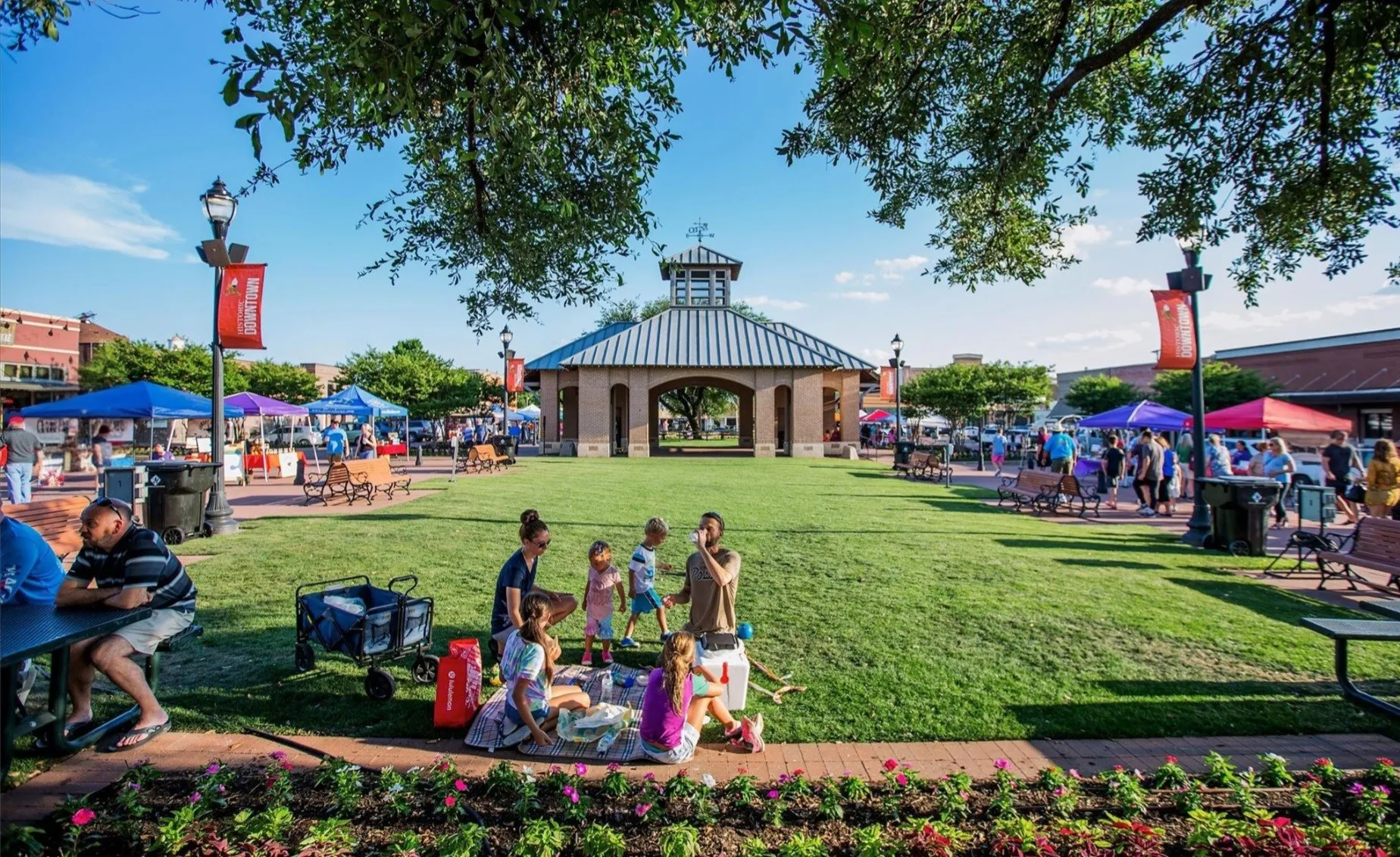 Expansive green space featuring a central gazebo with a metal roof, surrounded by paved walkways and established​​‌​​​​‌​​‌‌​‌‌​​​‌‌​‌​‌​‌​​​‌​​ trees