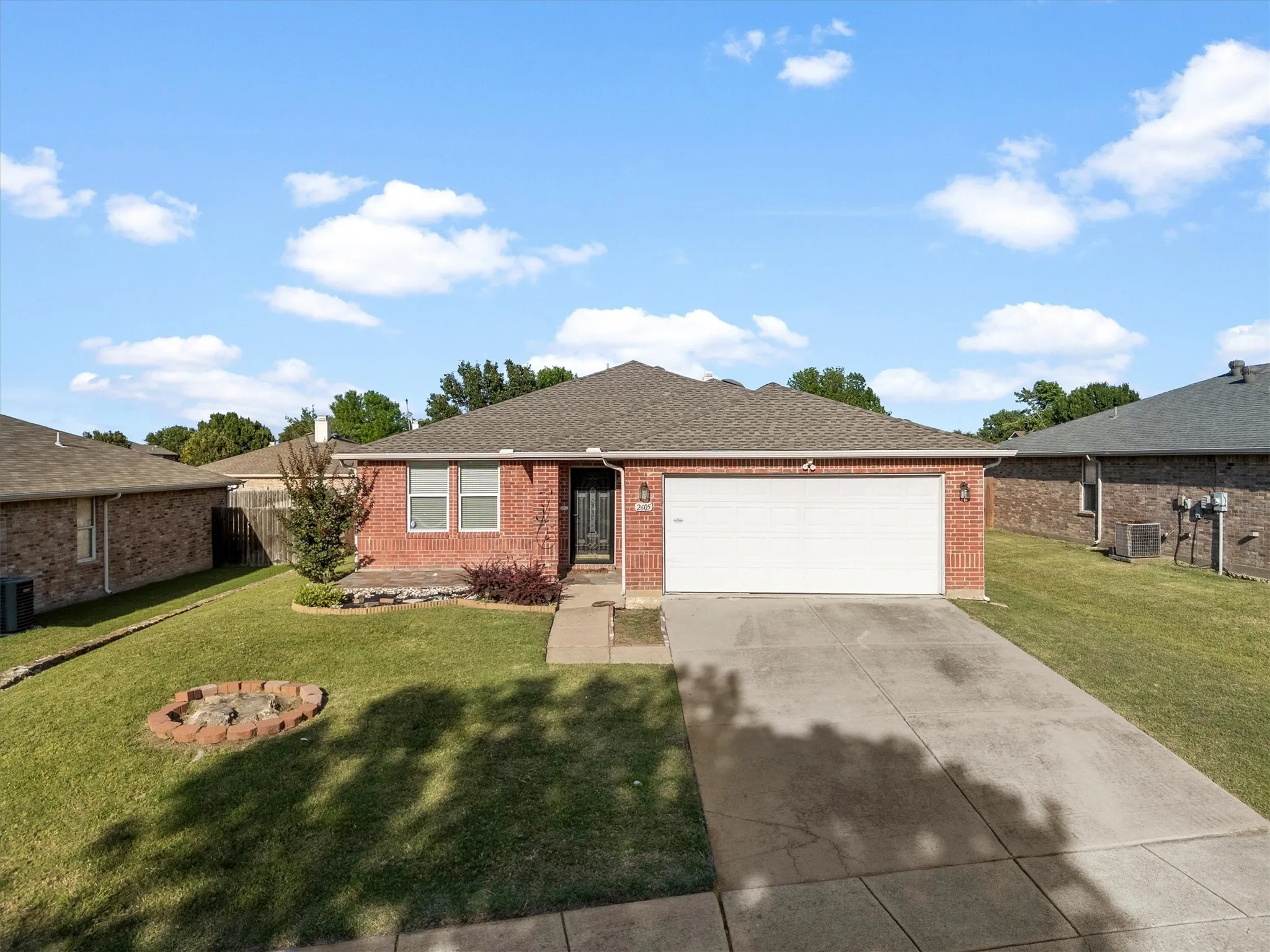 Brick facade residence featuring an attached two-car garage, concrete driveway, and a front walk leading to the entry