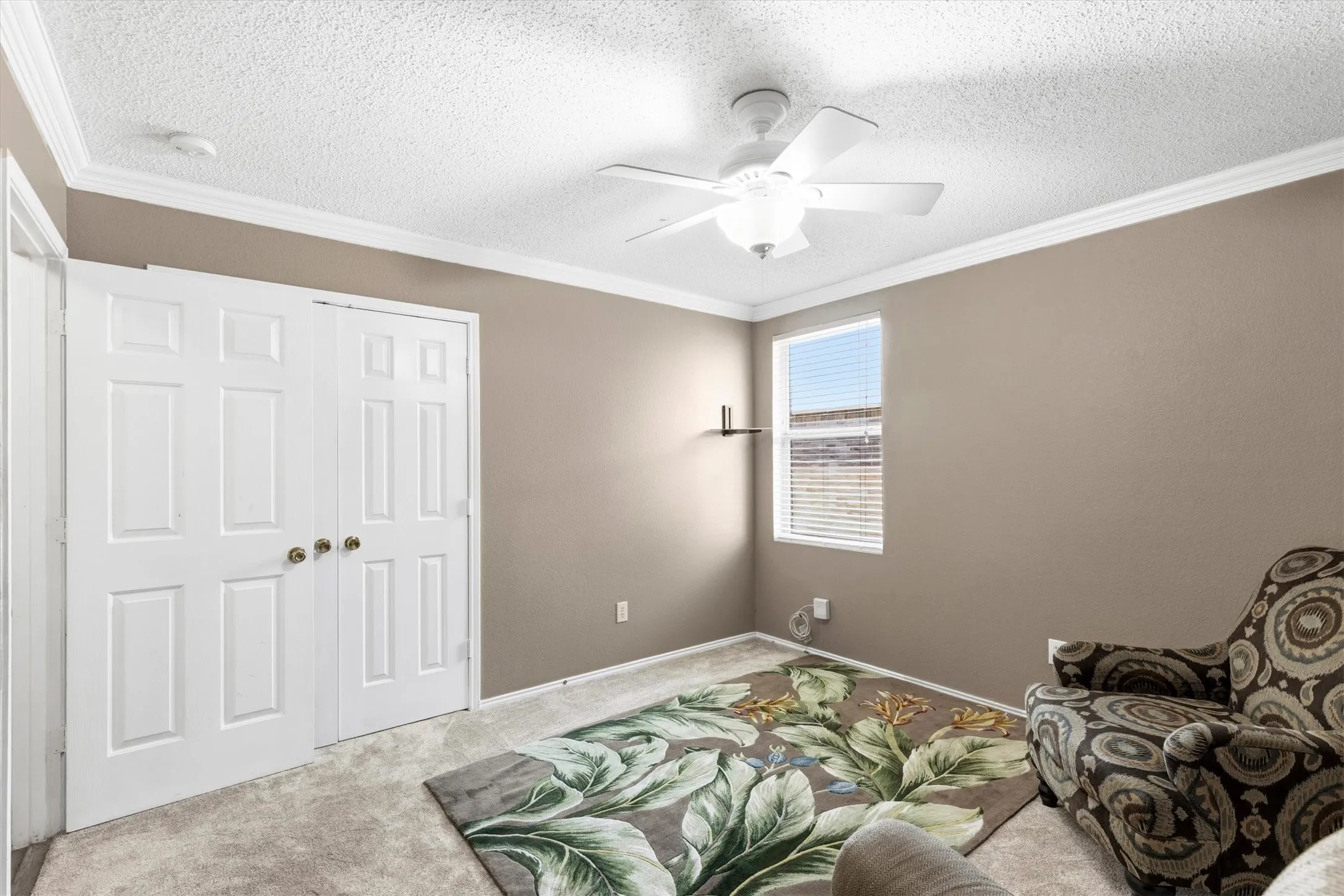 Room featuring neutral wall tones, crown molding, and textured ceiling