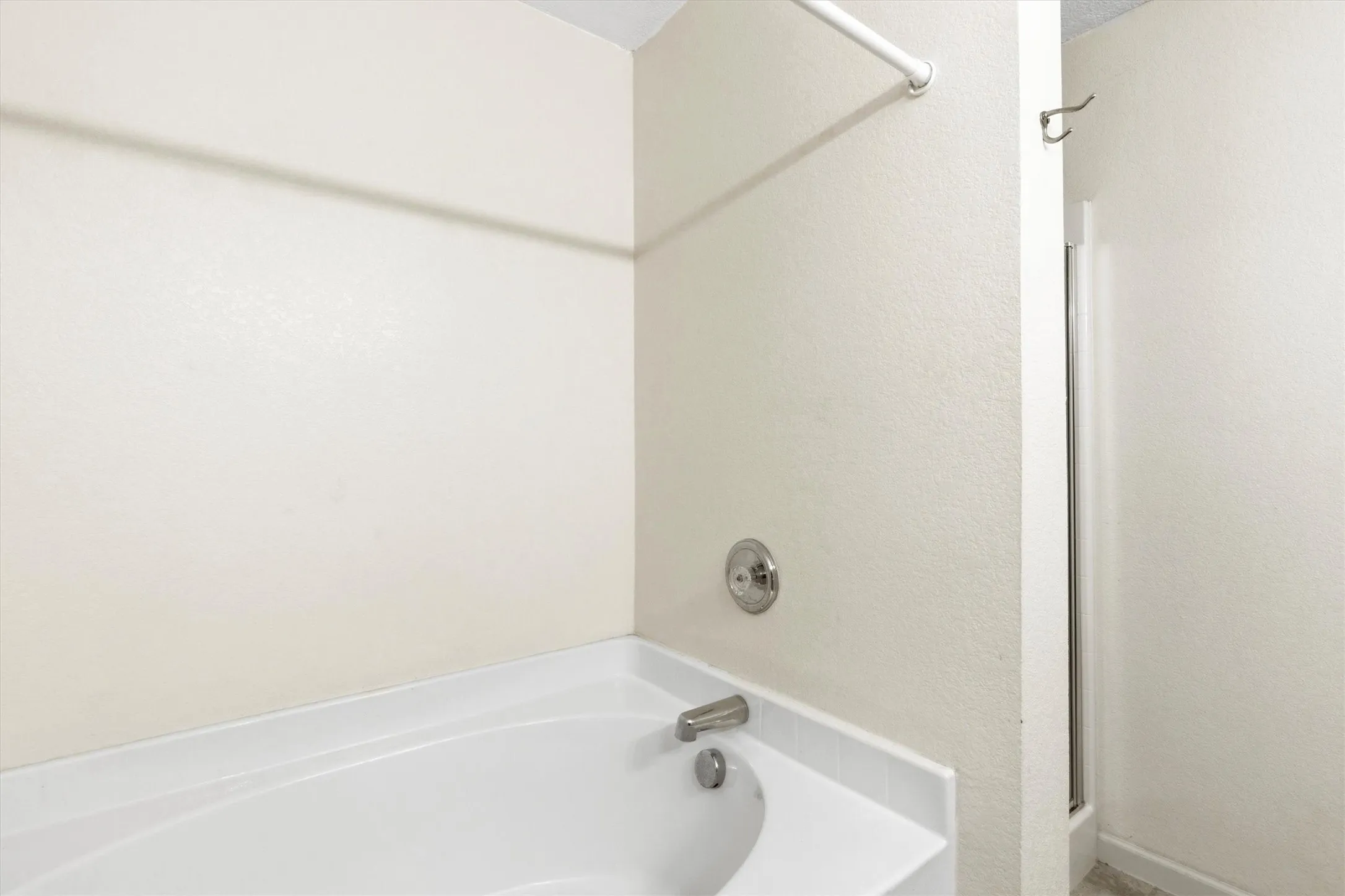 White drop-in bathtub with chrome fixtures and an adjacent standing shower with a glass enclosure