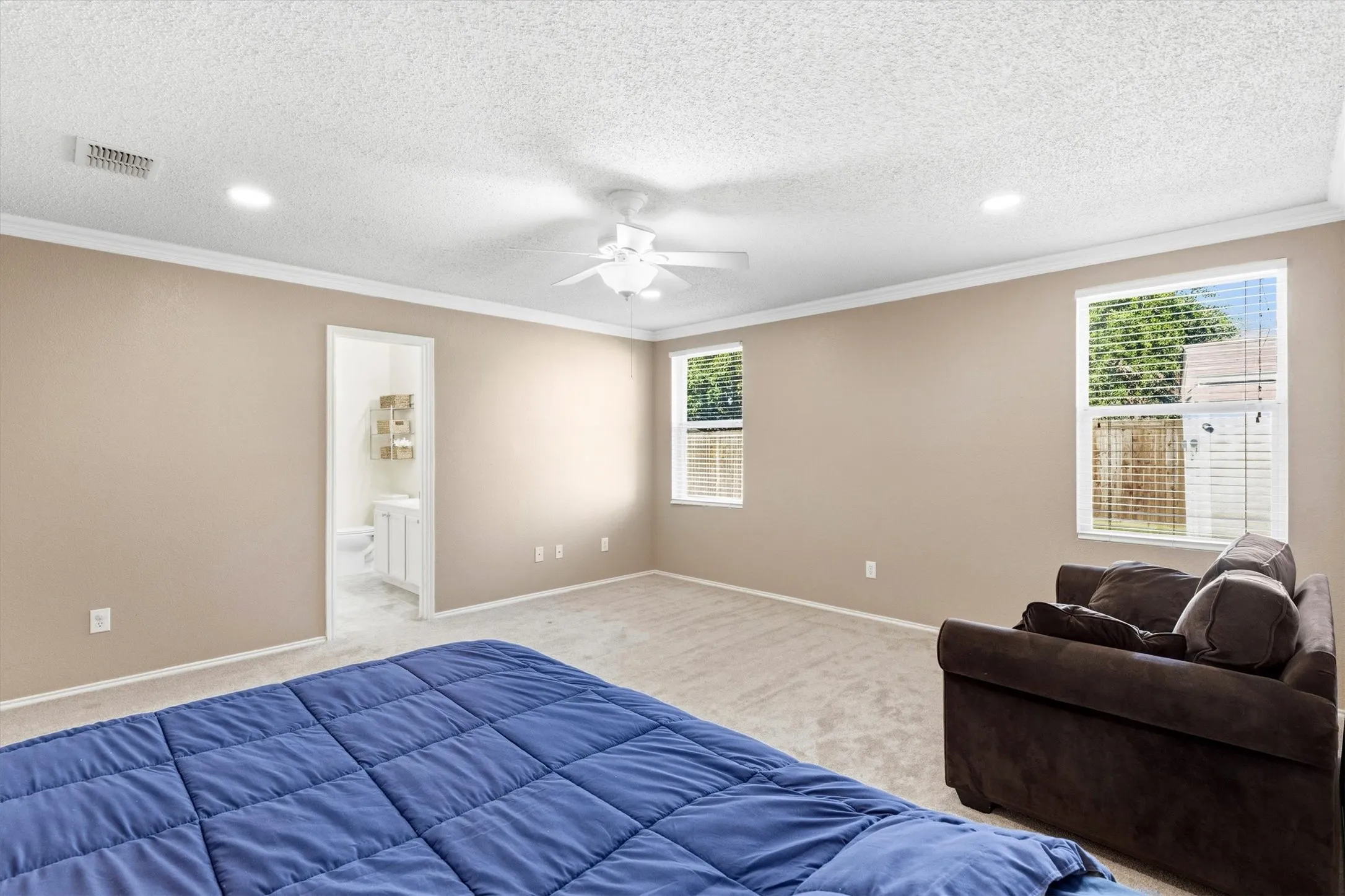 Spacious room featuring neutral tone walls, light-colored carpet flooring, recessed lighting, and a ceiling fan