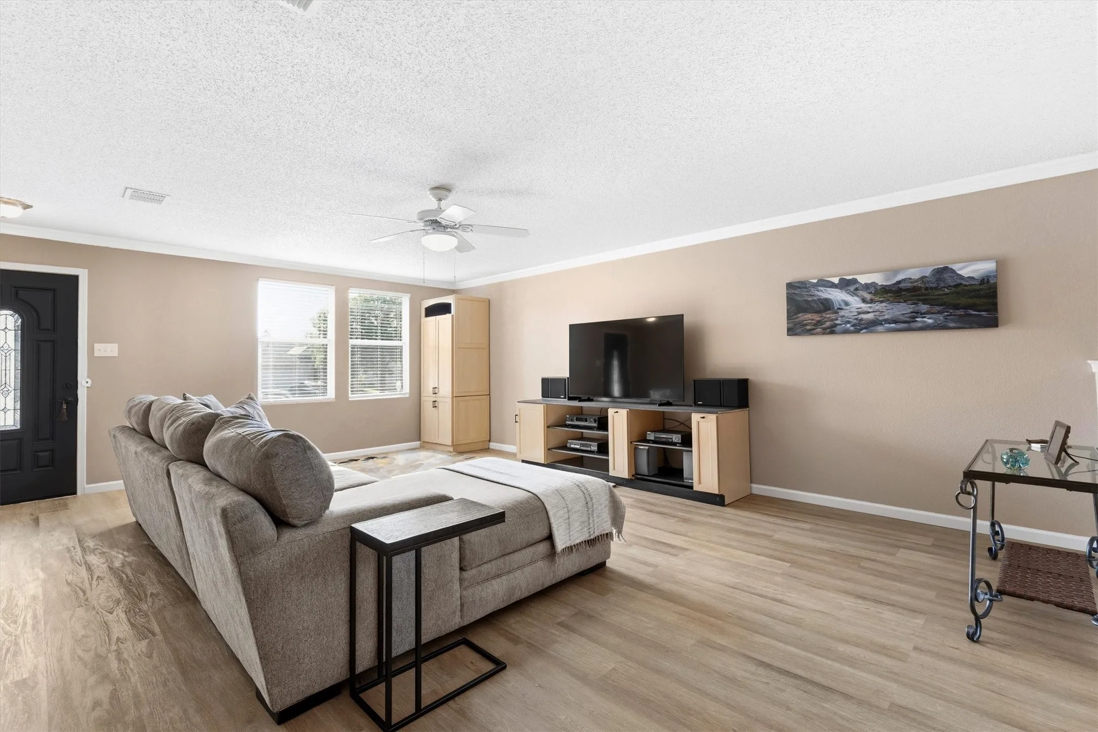Spacious living area featuring wood-finish flooring, neutral wall tones, and white crown molding