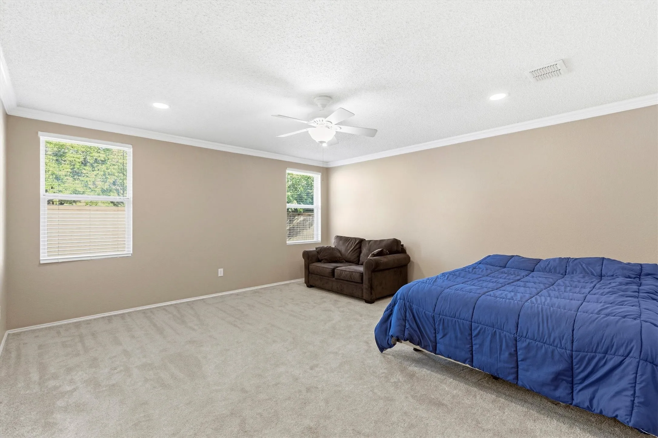 Spacious interior room featuring light gray carpeting, neutral wall tones, and white crown molding