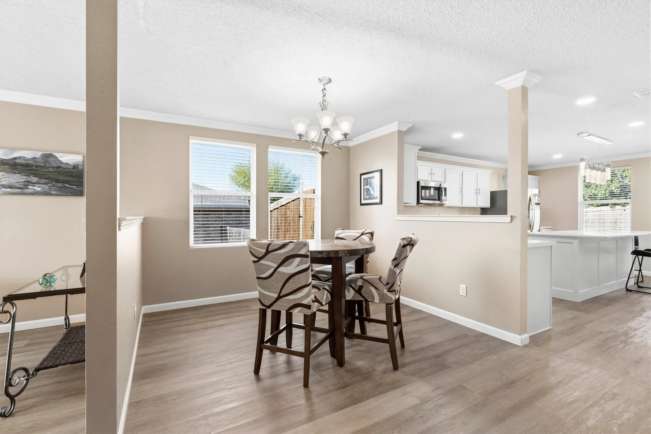 Open-concept living space featuring wood-finish flooring, recessed lighting, and crown molding