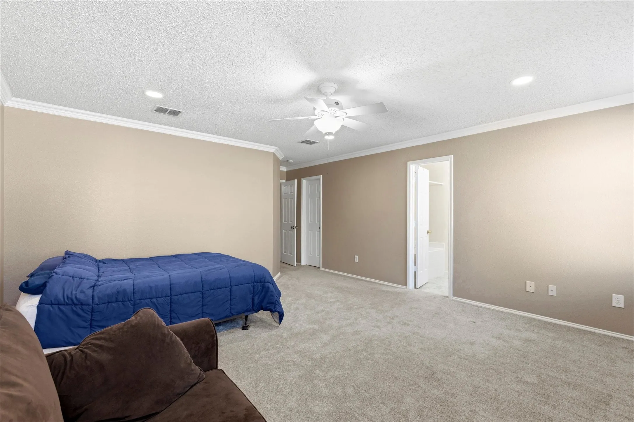 Expansive carpeted room featuring a ceiling fan, recessed lighting, crown molding, and two white paneled doors