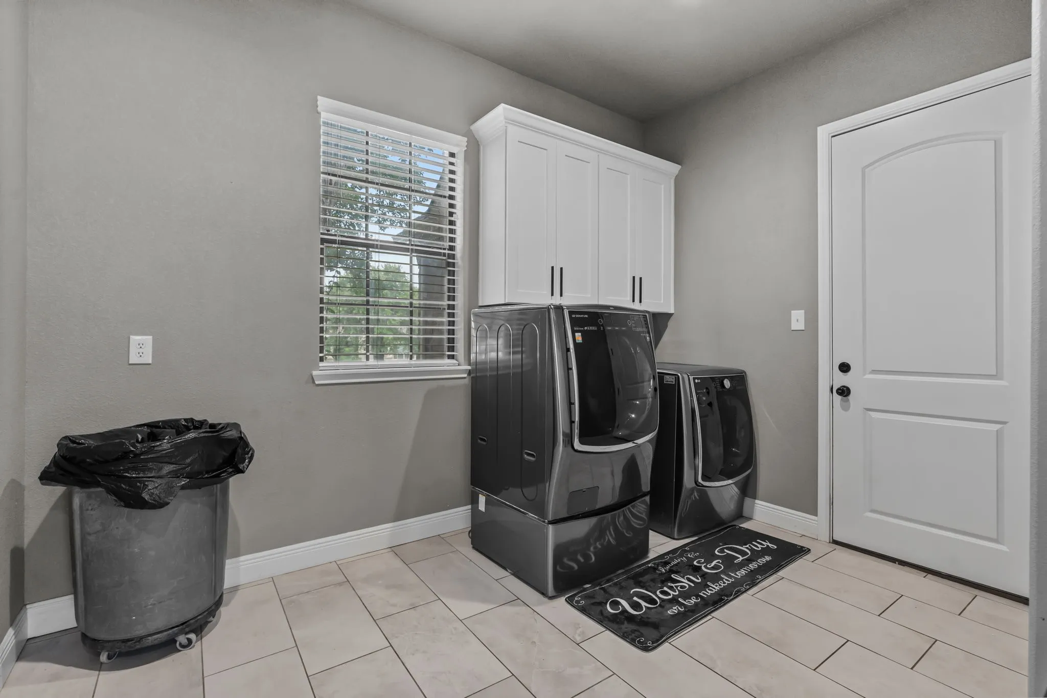 Laundry room with light tile patterned flooring, separate washer and dryer, and cabinets