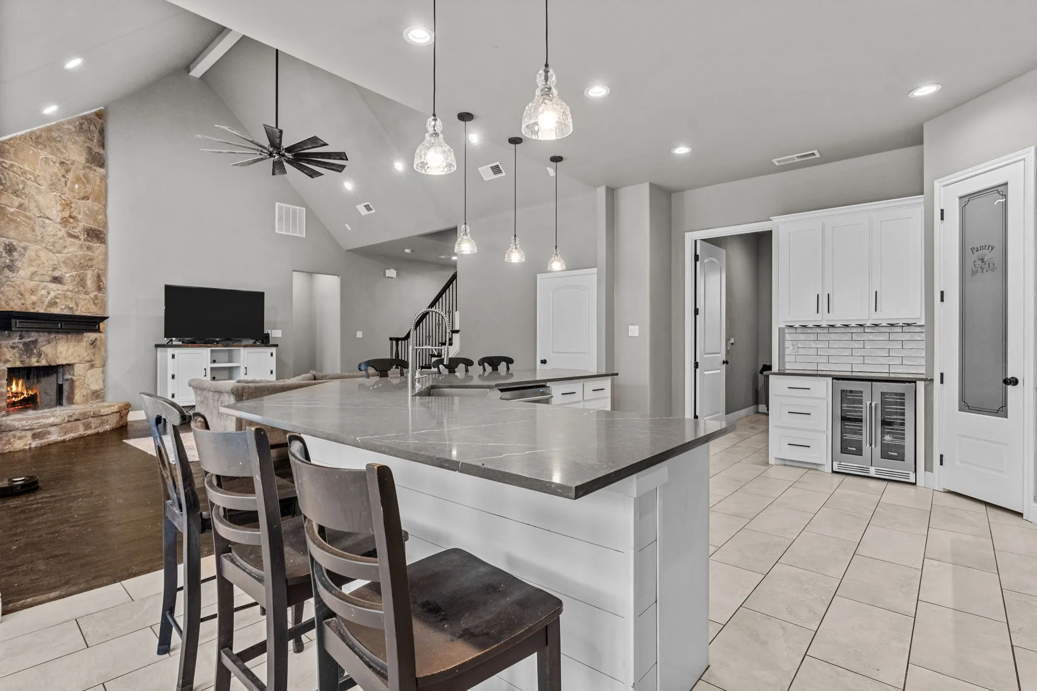 Kitchen featuring white cabinetry, tasteful backsplash, light hardwood / wood-style floors, a fireplace, and decorative light fixtures
