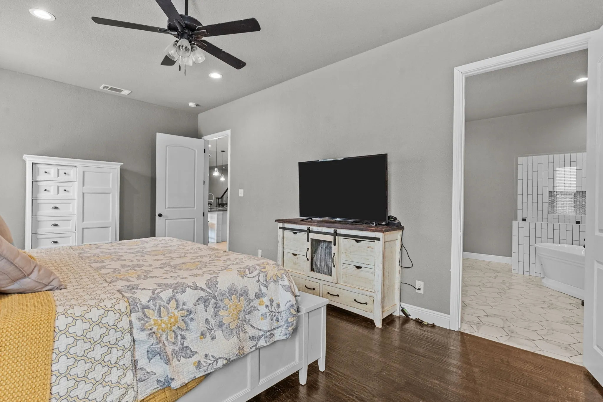 Bedroom featuring ensuite bath, hardwood / wood-style flooring, and ceiling fan