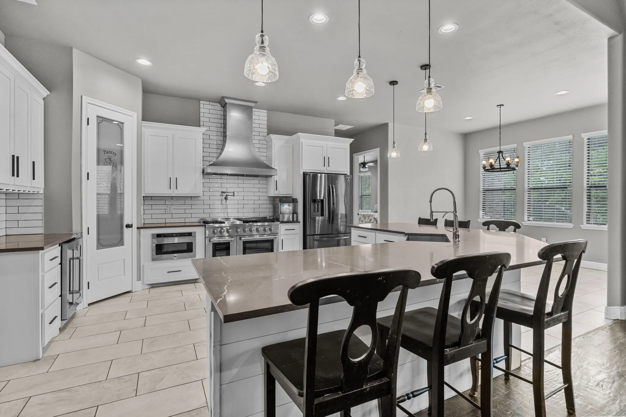 Kitchen with a large island with sink, stainless steel appliances, backsplash, and custom range hood