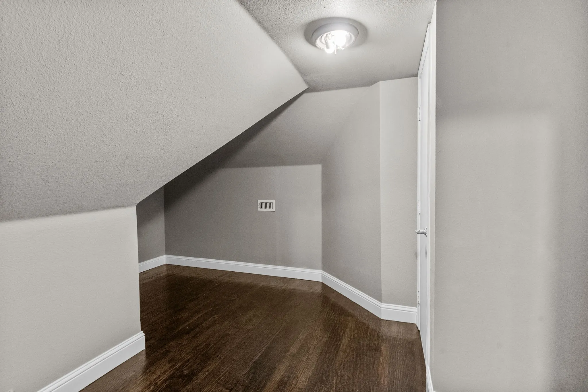 Additional living space featuring hardwood / wood-style flooring, vaulted ceiling, and a textured ceiling
