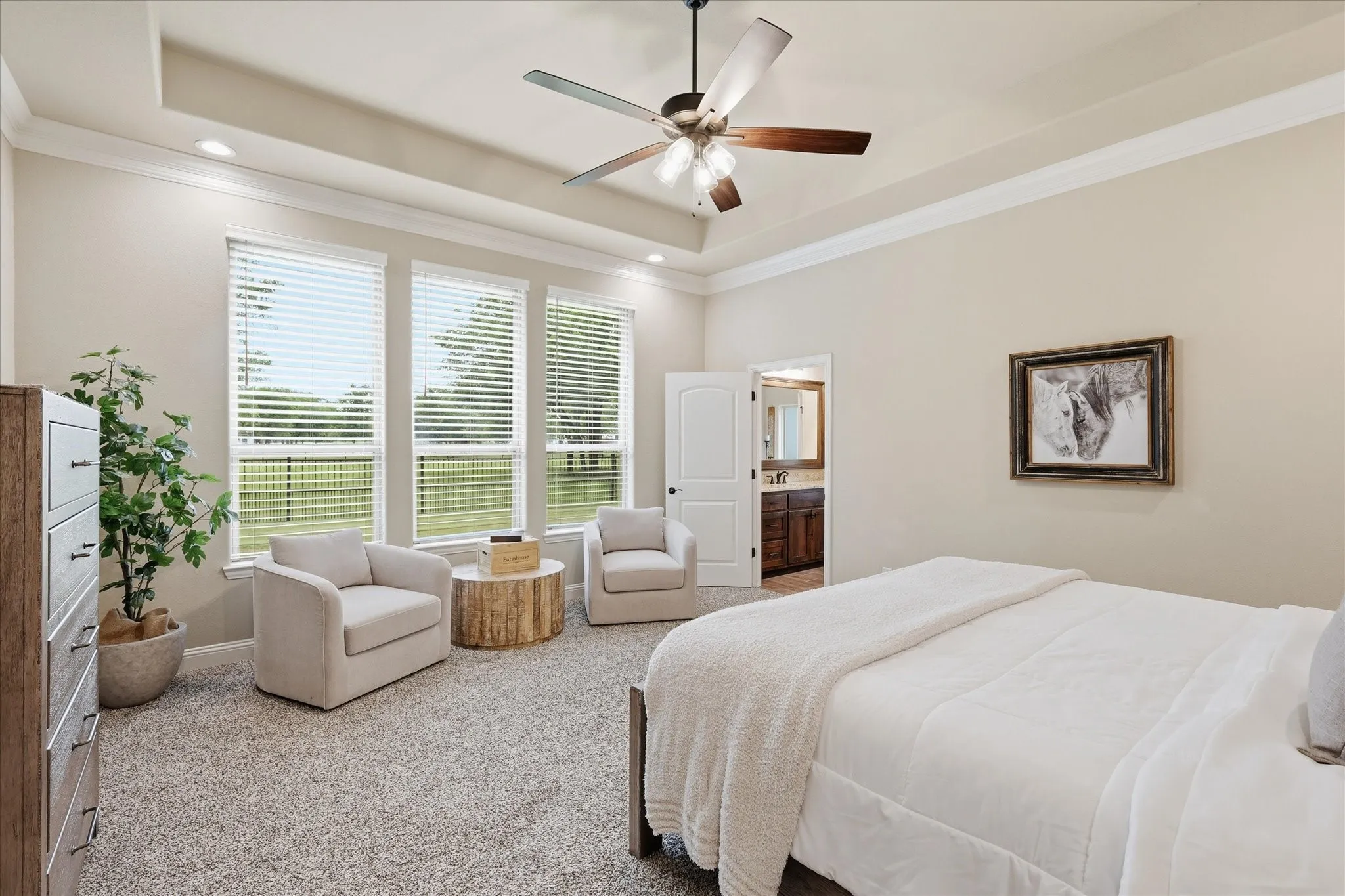 Spacious bedroom featuring a tray ceiling with crown molding, recessed lighting, and a ceiling fan
