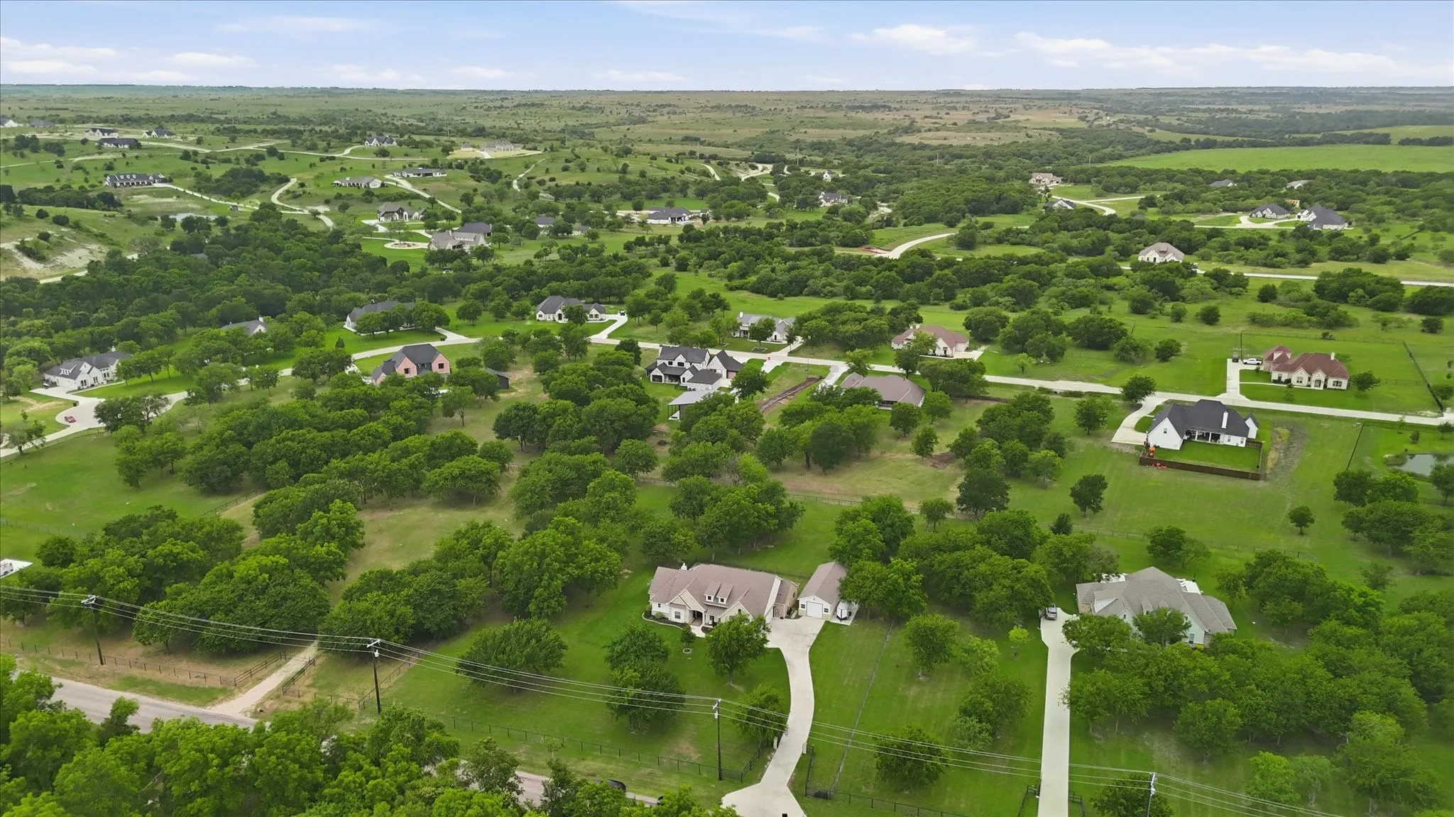 Expansive aerial showcasing a residential area featuring numerous single-family homes set among abundant mature trees and verdant green spaces
