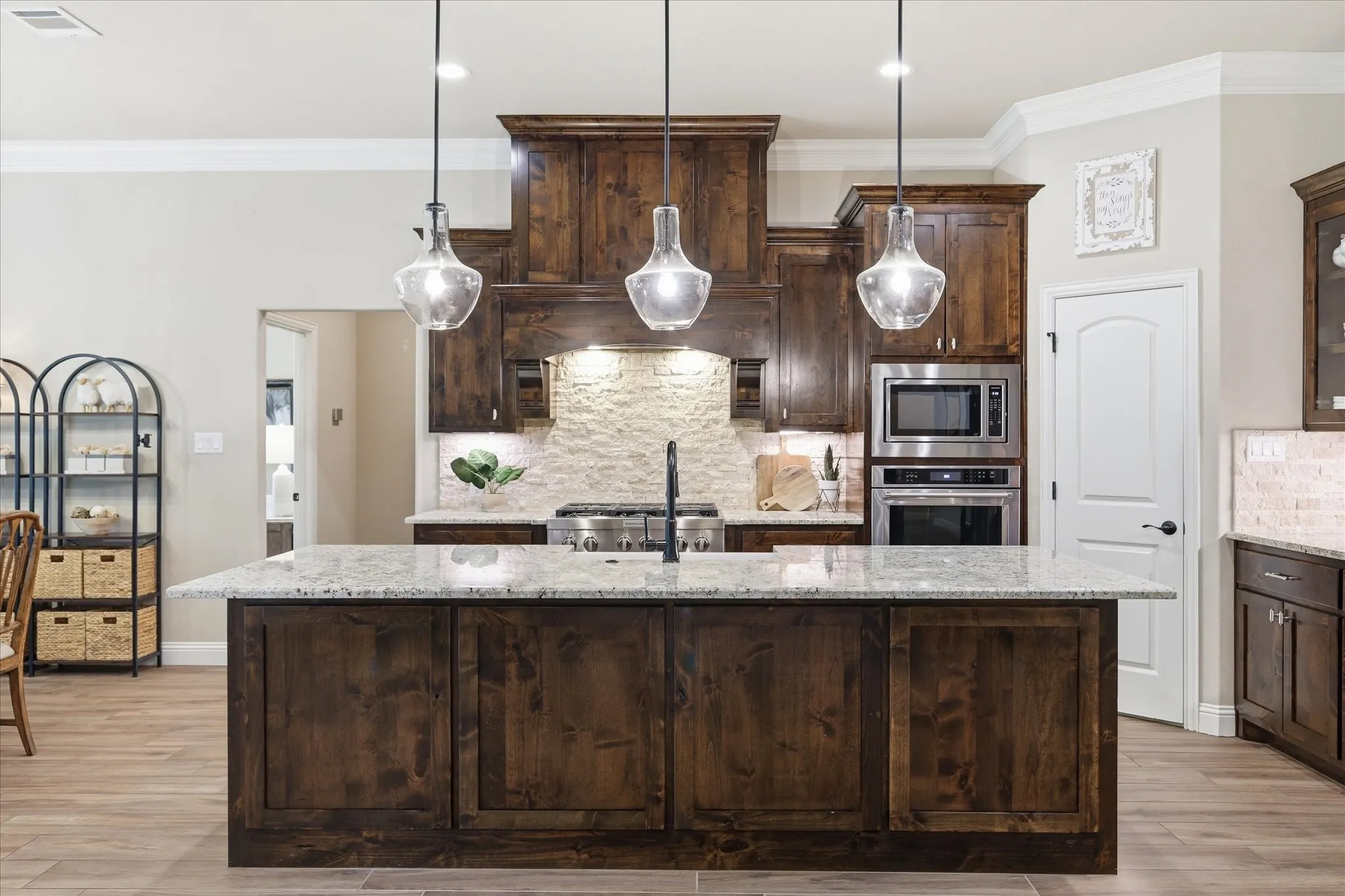 Kitchen island with a light-toned countertop, dark wood-finish cabinetry, and three clear glass pendant lights