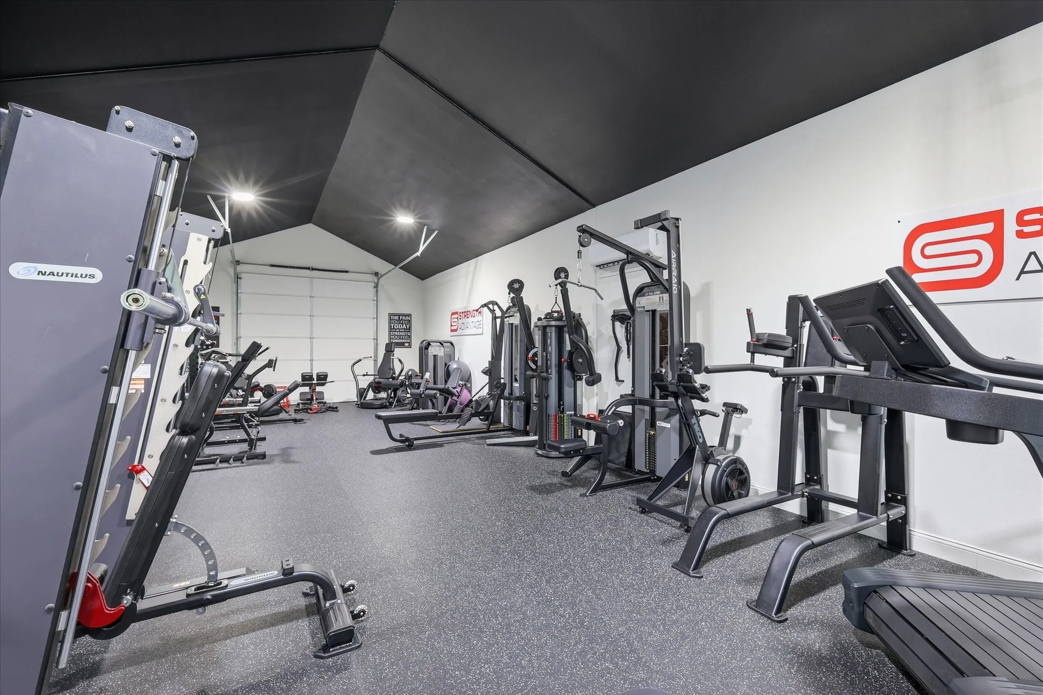 Dedicated fitness space featuring a pitched black ceiling, white walls, and a durable rubber flooring surface