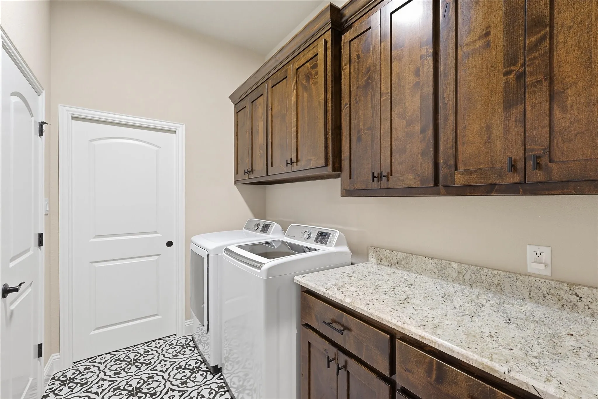 Laundry area featuring extensive wood cabinetry, light-toned countertops, and decorative floor tiling