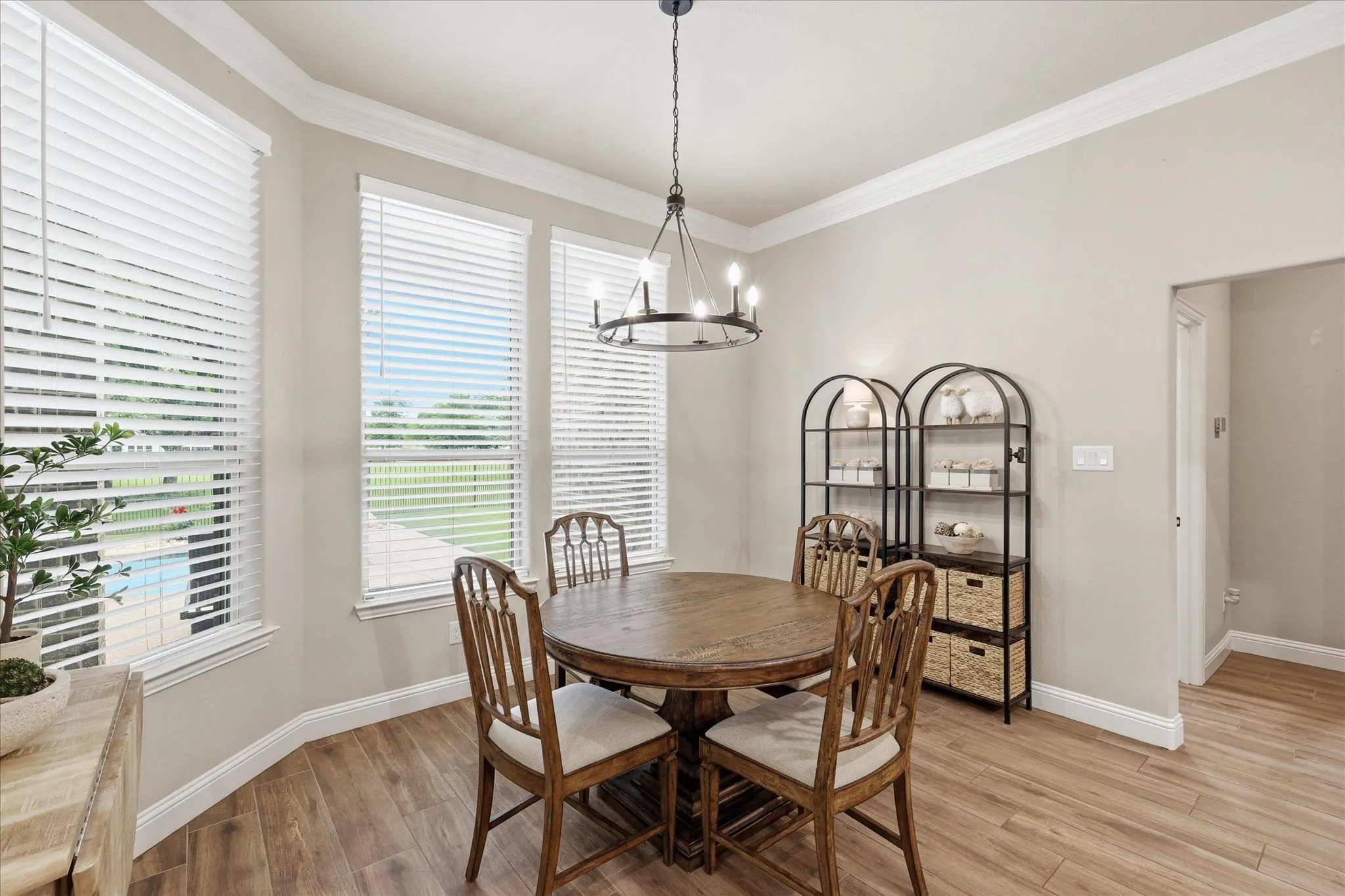 Dining area featuring wood-finish flooring, a contemporary chandelier, and a bay window with white blinds