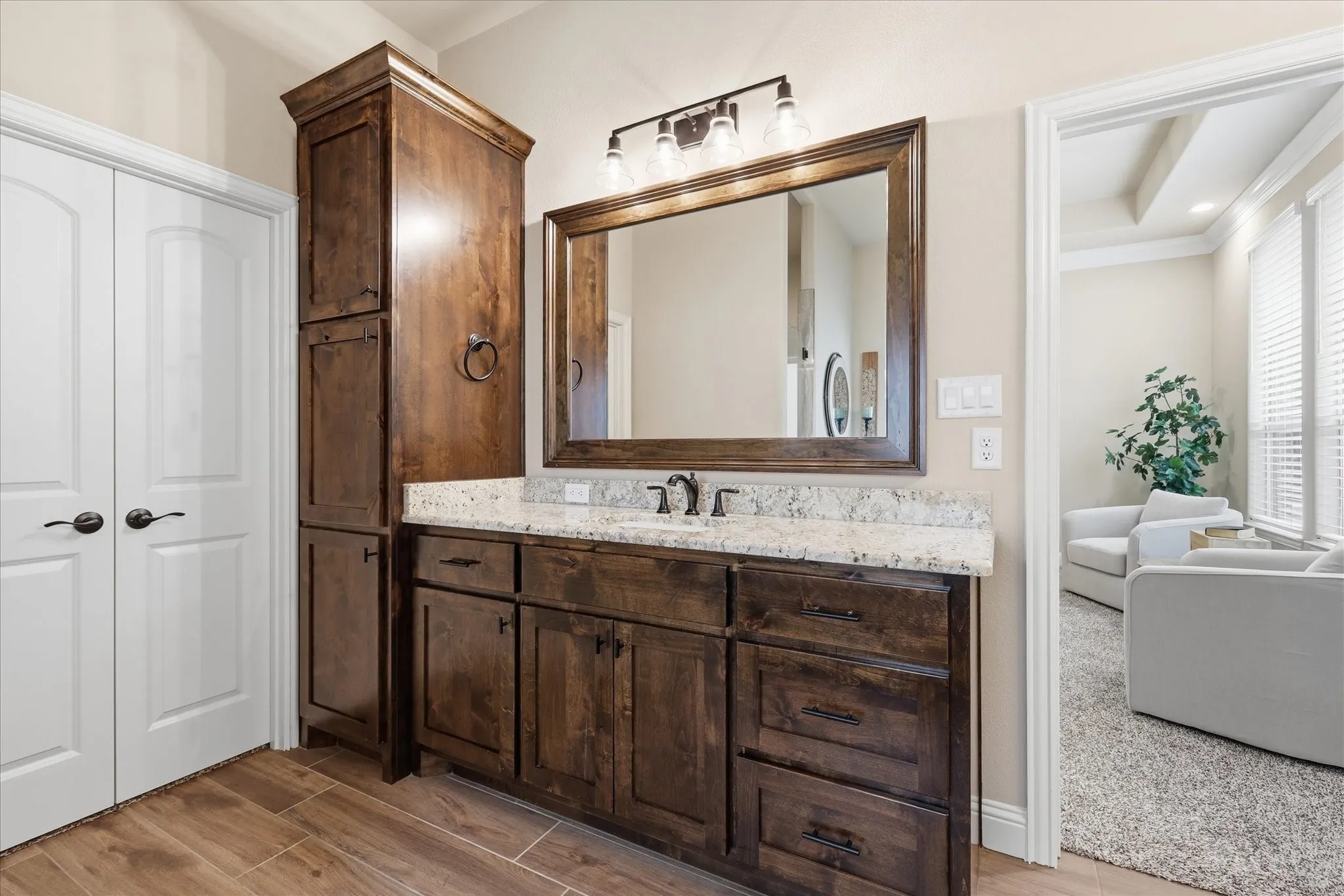 Bathroom vanity featuring dark wood cabinetry, a light-toned countertop, and a framed mirror with a mounted light fixture