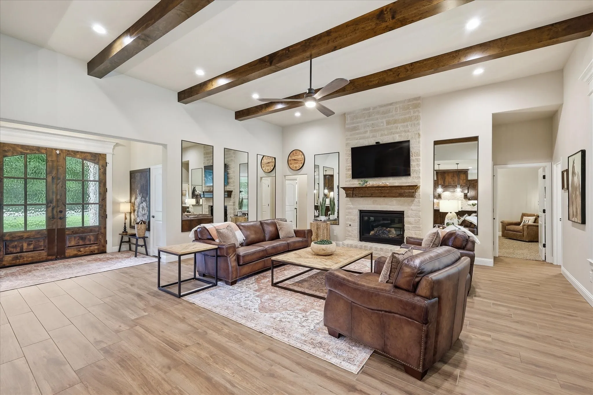 Spacious living area featuring exposed ceiling beams, recessed lighting, and light wood-finish flooring