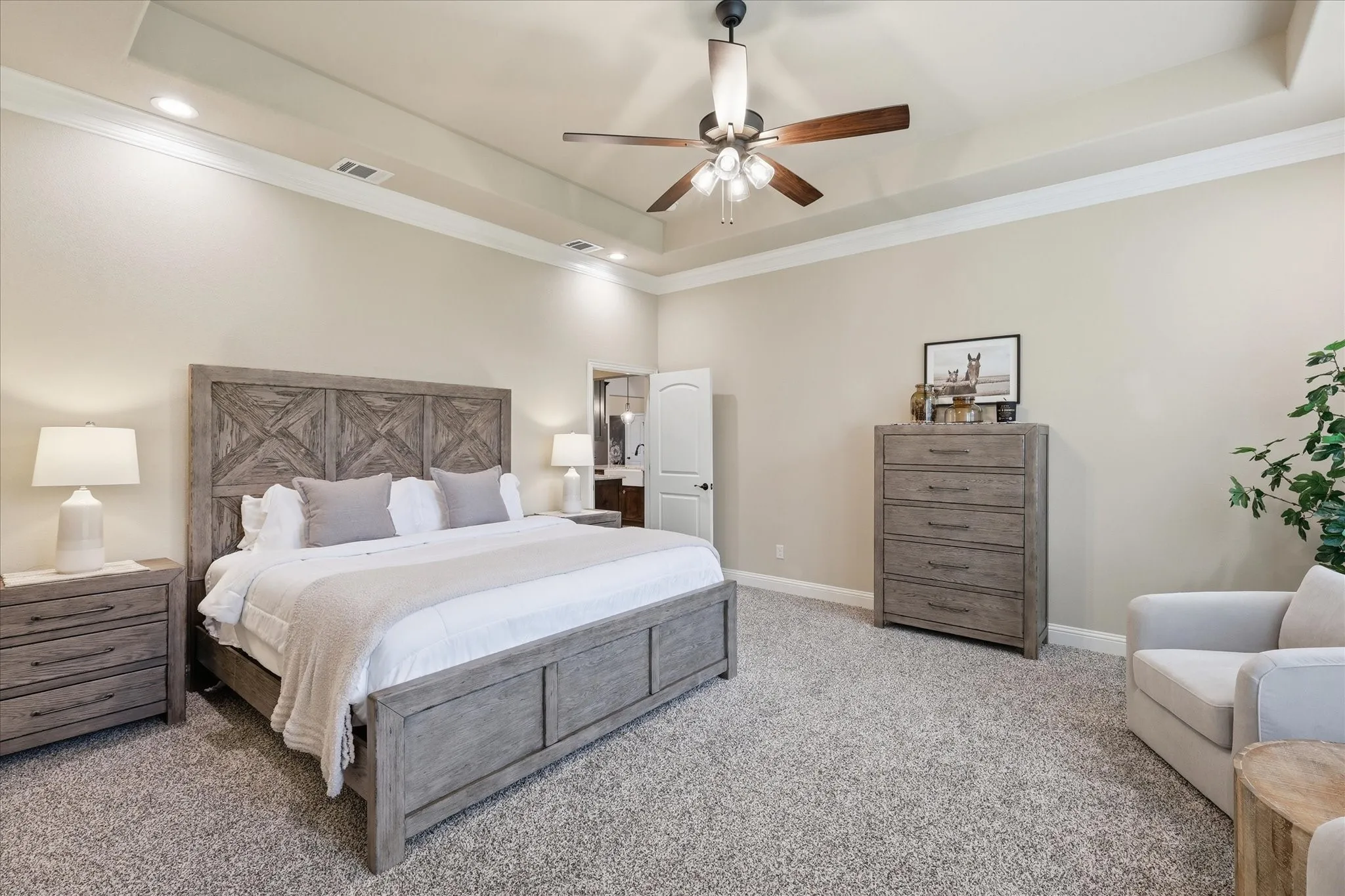 Spacious bedroom featuring plush carpeting and a tray ceiling with crown molding