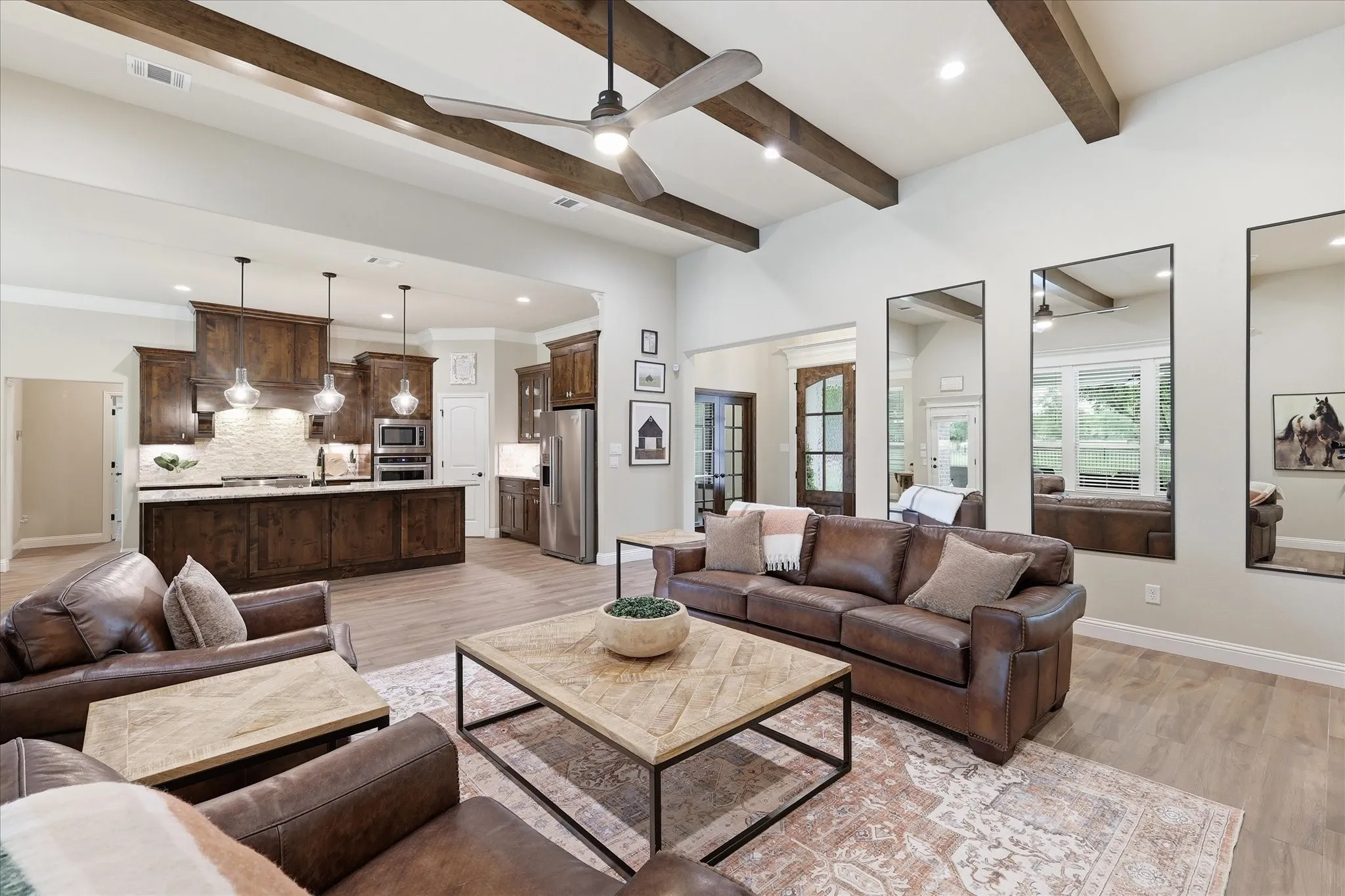 Vaulted ceilings with exposed wood beams, a ceiling fan, and recessed lighting create a bright living space