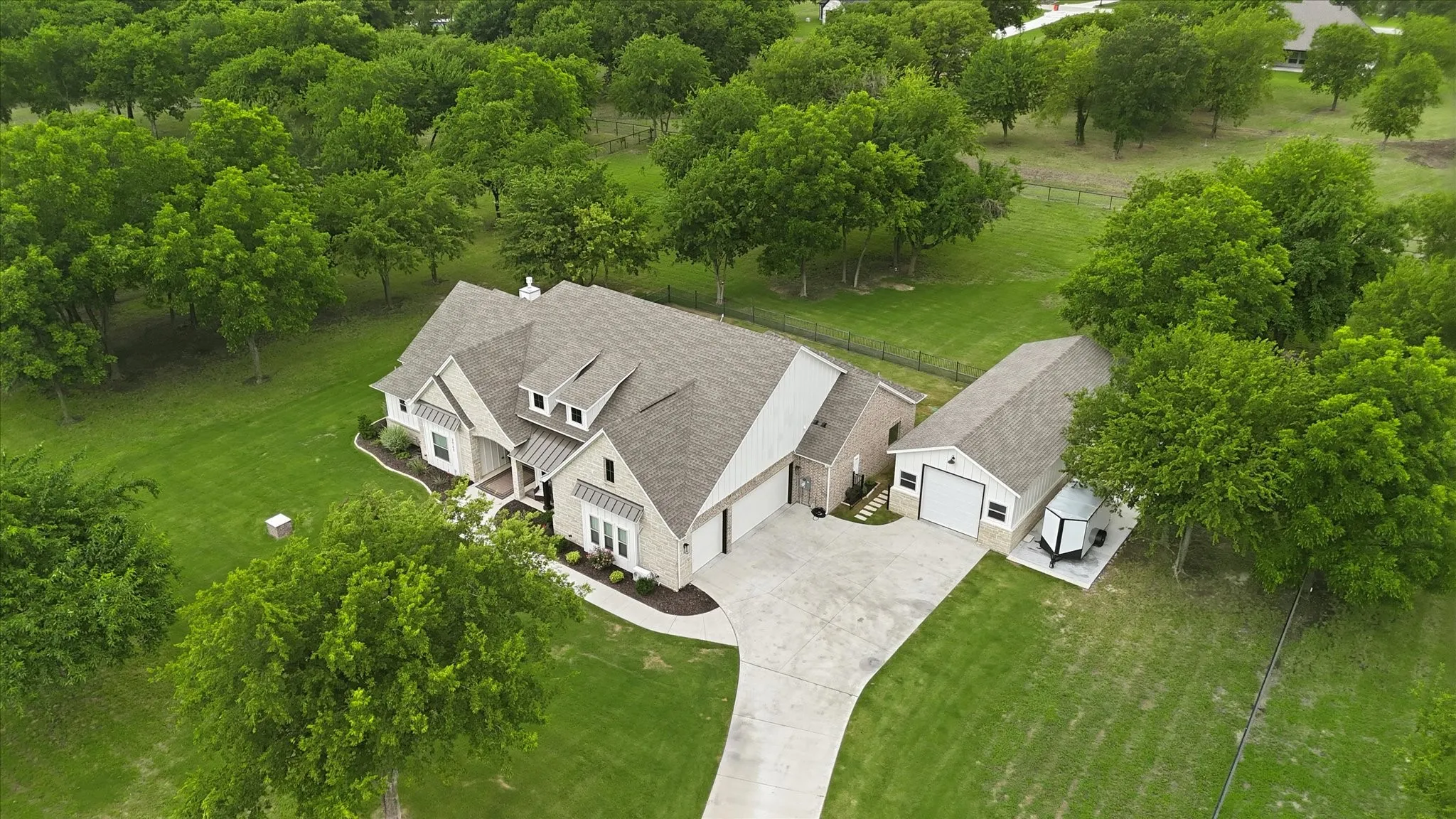 Spacious property featuring a large residence with a multi-gabled roofline, light-colored brick and siding facade, and an attached two-car garage