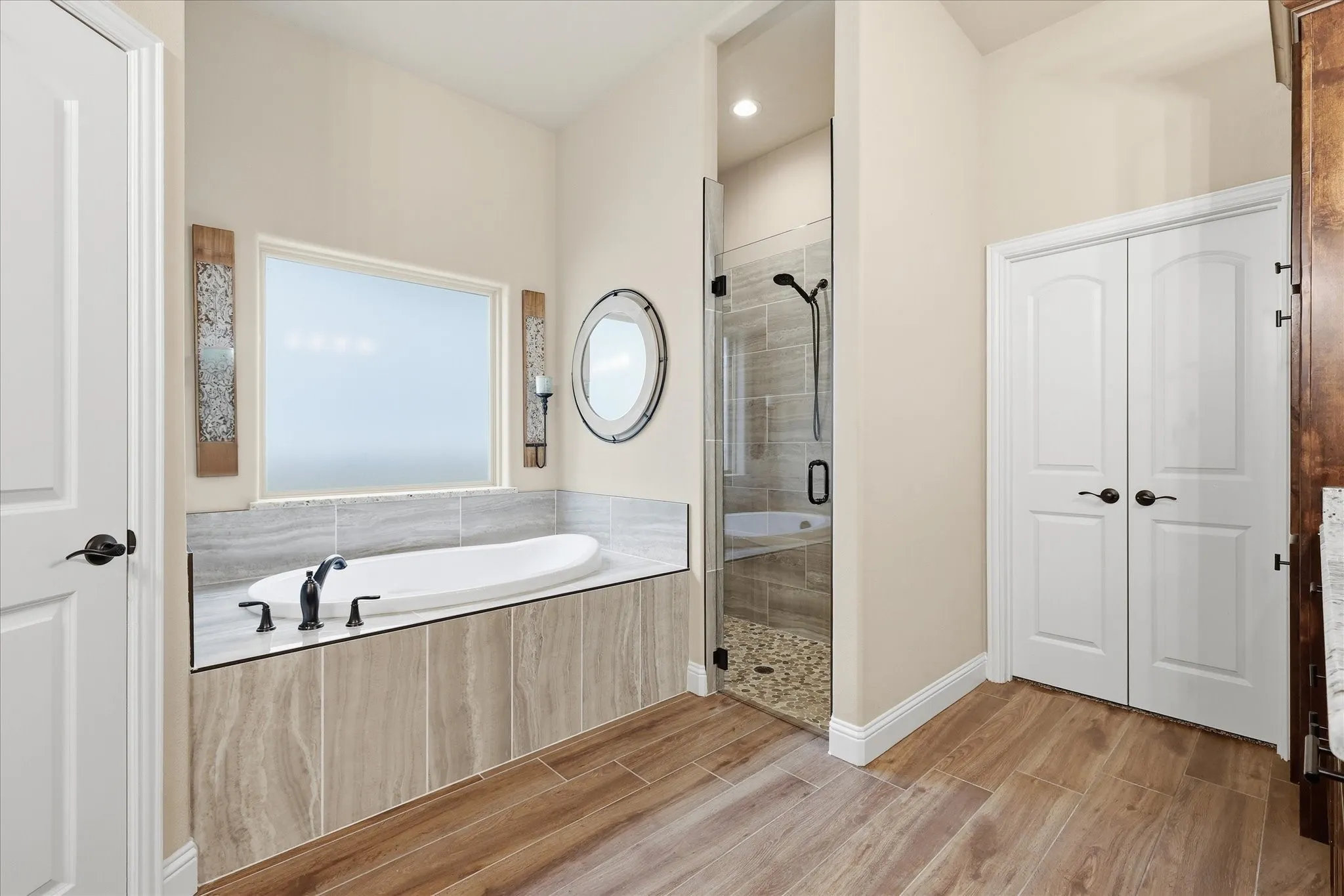 Soaking tub with matte black fixtures, set in a tiled surround with stone-finish countertop