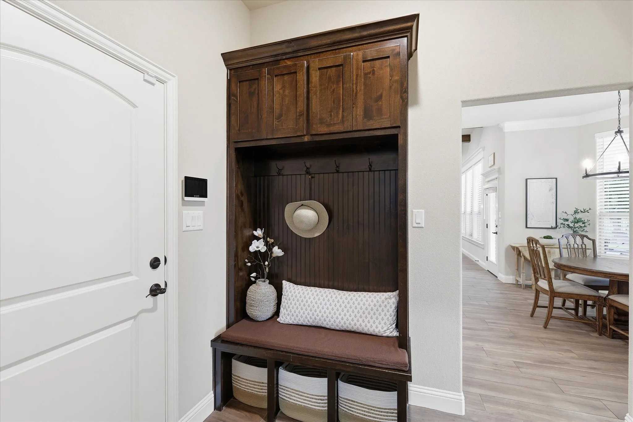 Built-in mudroom bench with dark wood finish, beadboard paneling, and upper storage cabinetry