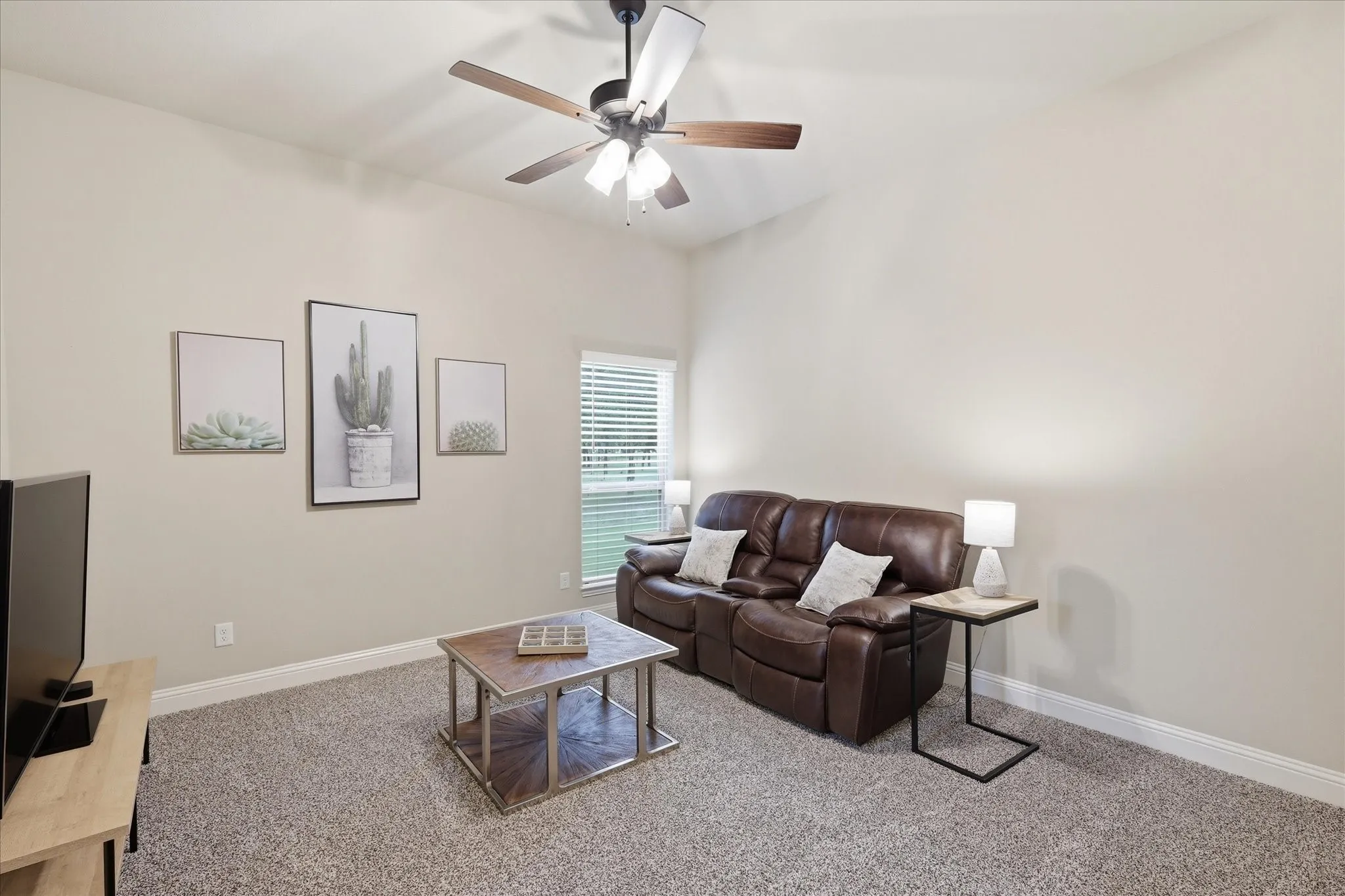 Living area featuring a vaulted ceiling with a ceiling fan, light neutral wall tones, and carpet flooring